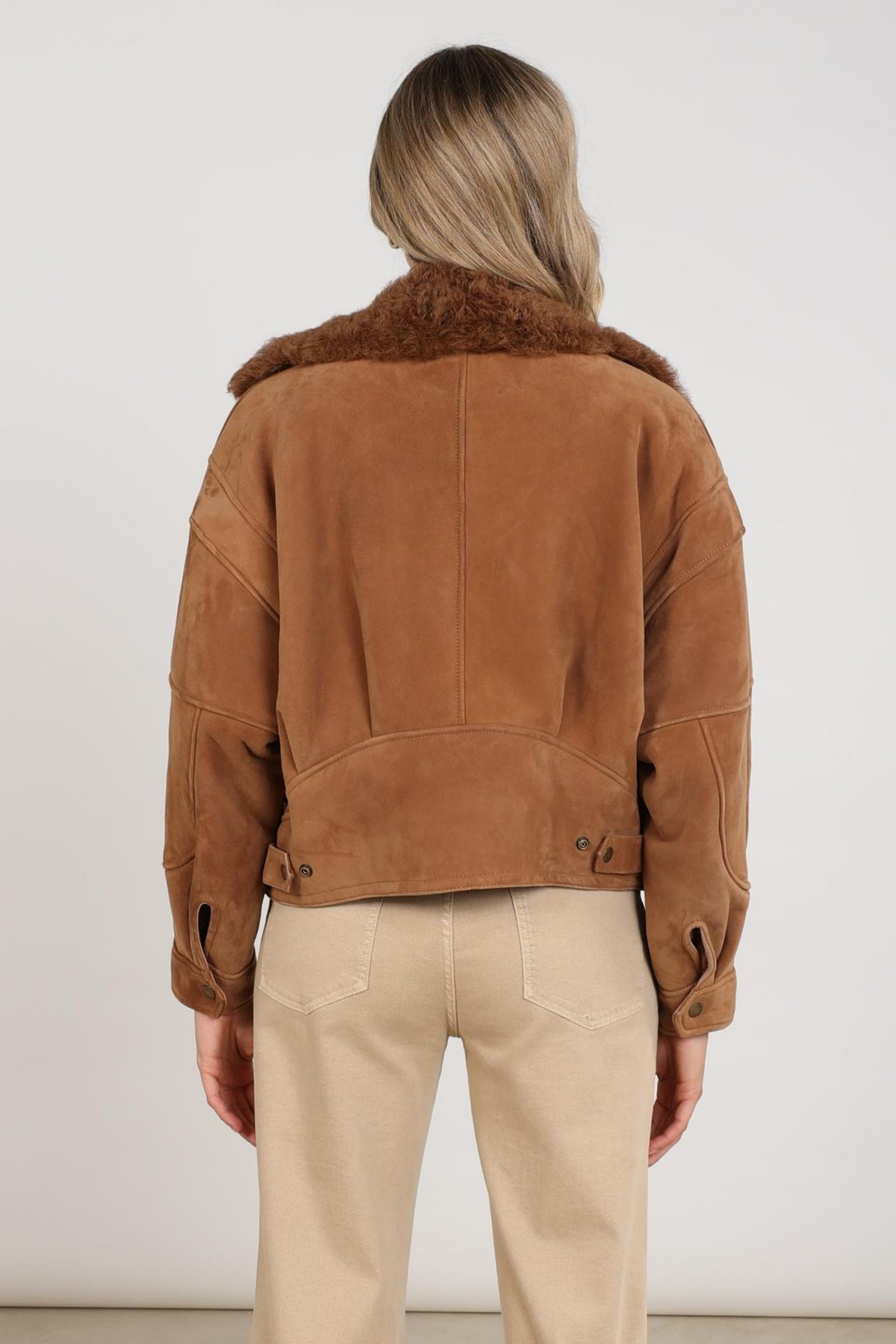 Nukus Evita Toffee jas voor dames, donkerbruine winterjas met capuchon en ritssluiting, gedragen door model.