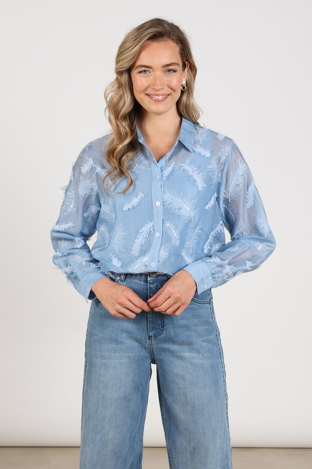 Blouse Aysha met veren in skyblauw van Nukus, elegante damesblouse met zachte stof en gedetailleerde afwerking.