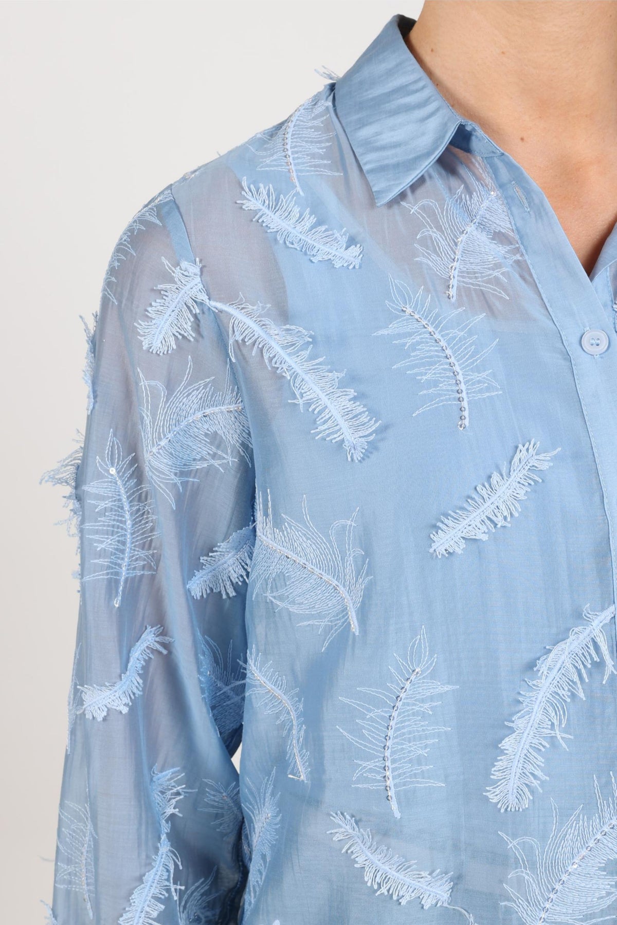Blouse Aysha Feathers Sky van Nukus met luchtige stof en kleurrijke vogelprint, zichtbaar op de afbeelding.