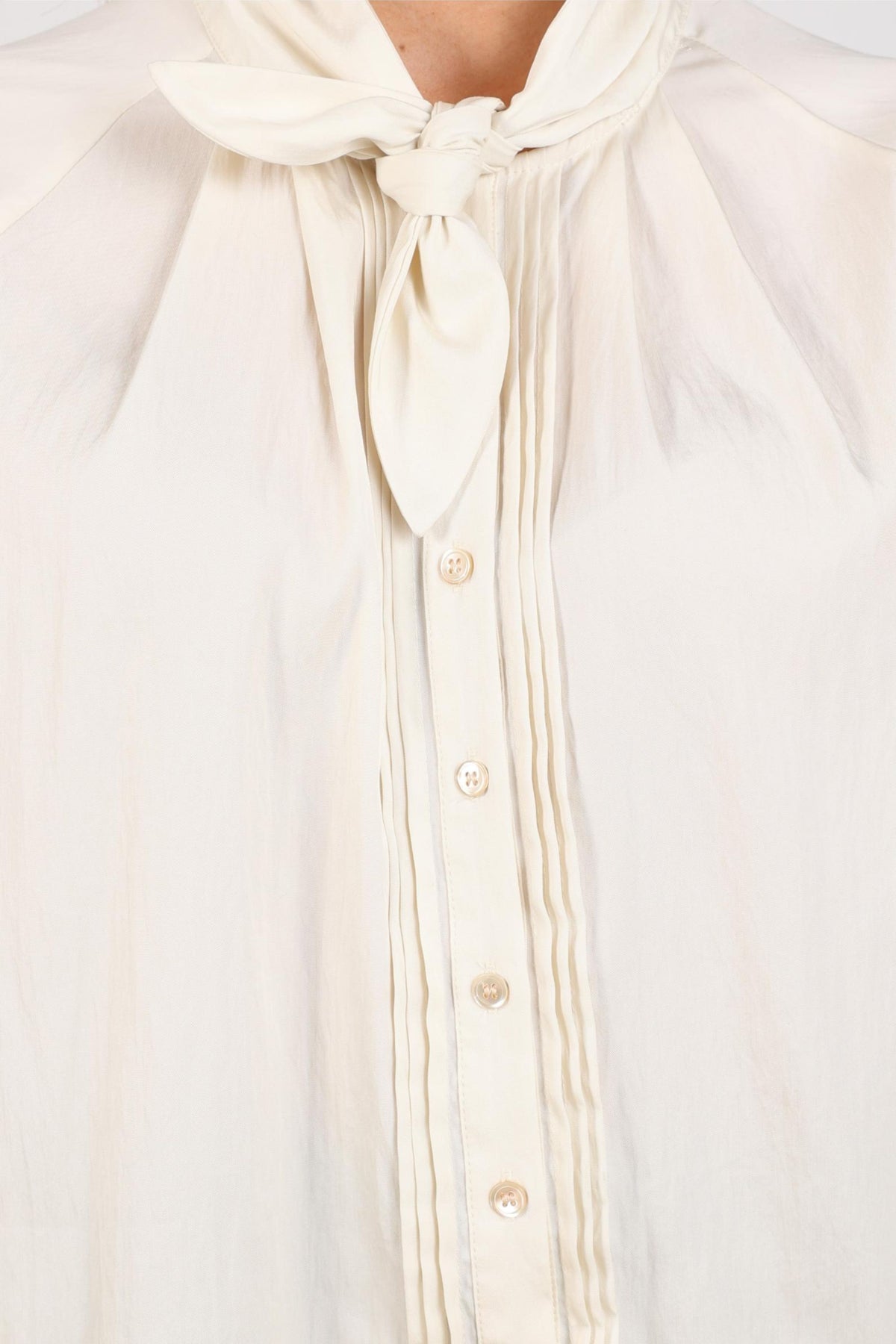 Offwhite blouse Alexandra van Nukus, met ronde hals en lange mouwen, gedragen door een model op een neutrale achtergrond.