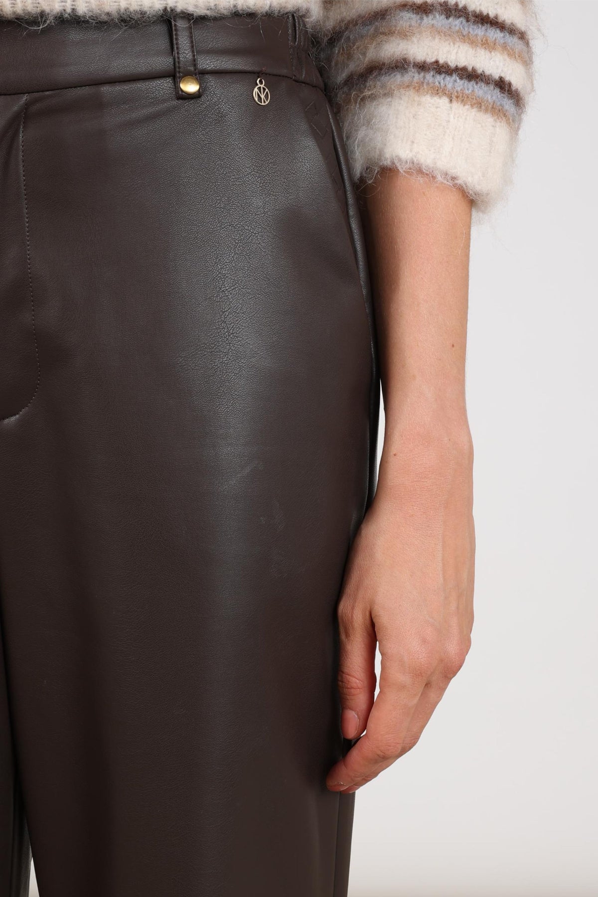 Bruine Nukus Beverly PU broek met rechte snit en elastische tailleband, gelegen op een witte achtergrond.