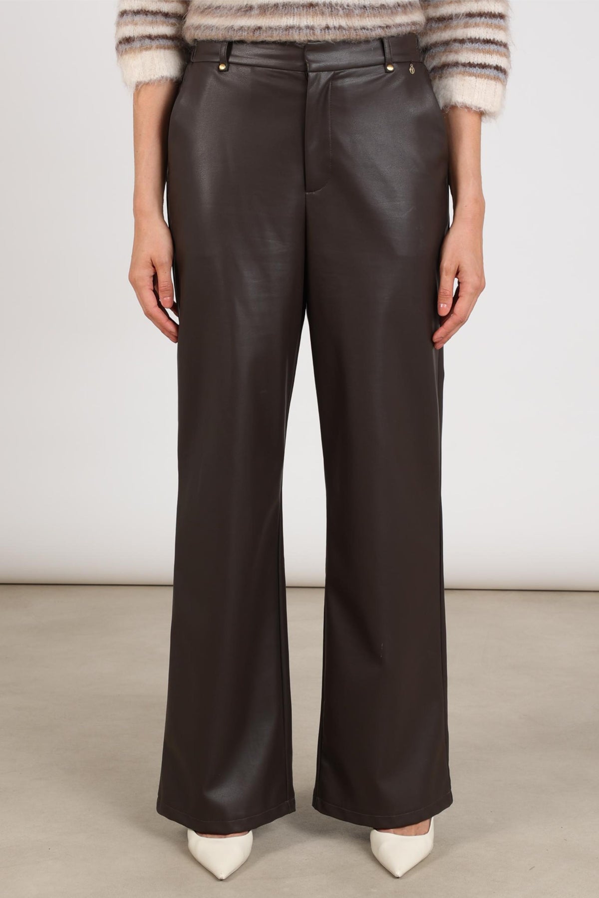 Donkere chocolade bruine Nukus Beverly PU broek met rechte pasvorm en elastische taille, gedragen door een model.
