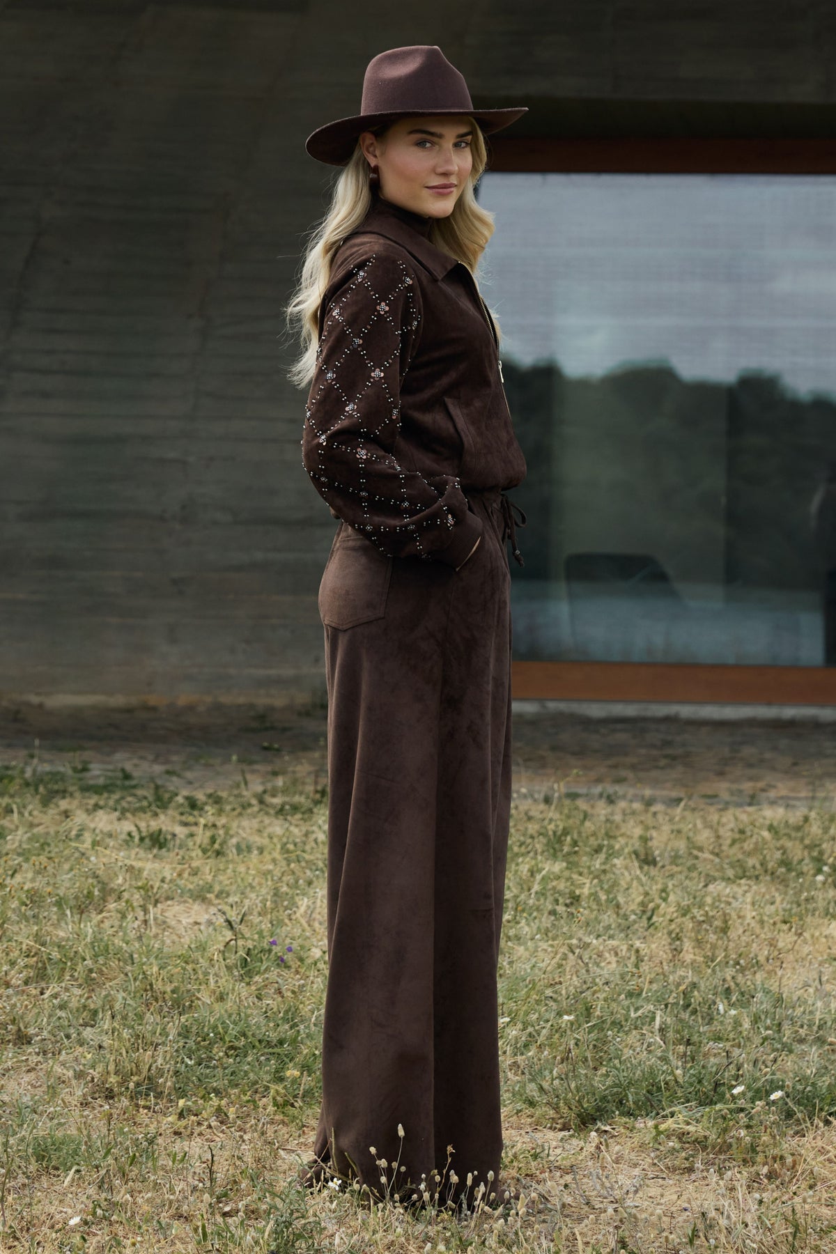 Donkere chocolade suède broek van Nukus, model Bertie, met een losse pasvorm en stijlvolle details, zichtbaar in de afbeelding.