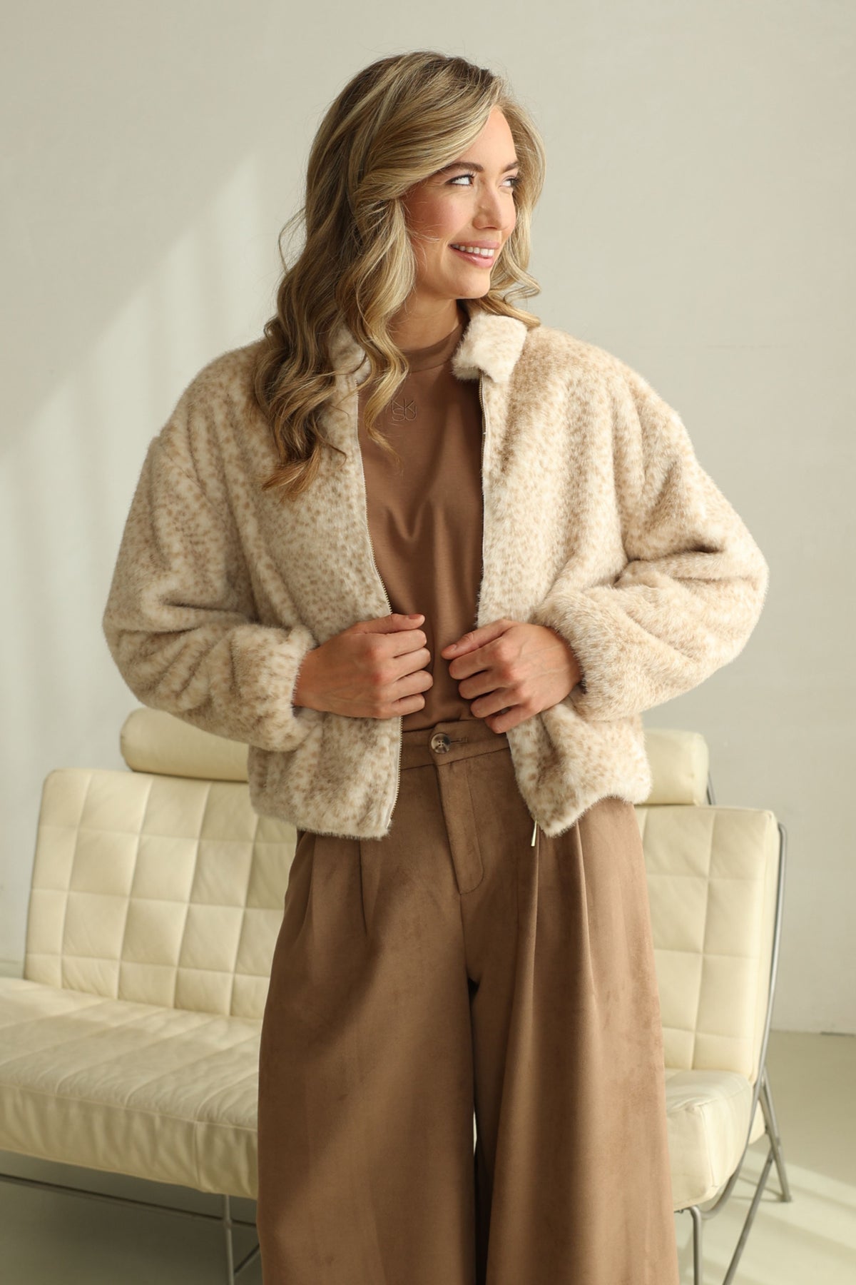 Nukus Bambi Sand jas voor dames, lichtgewicht met capuchon en ritssluiting, gedragen door een model.