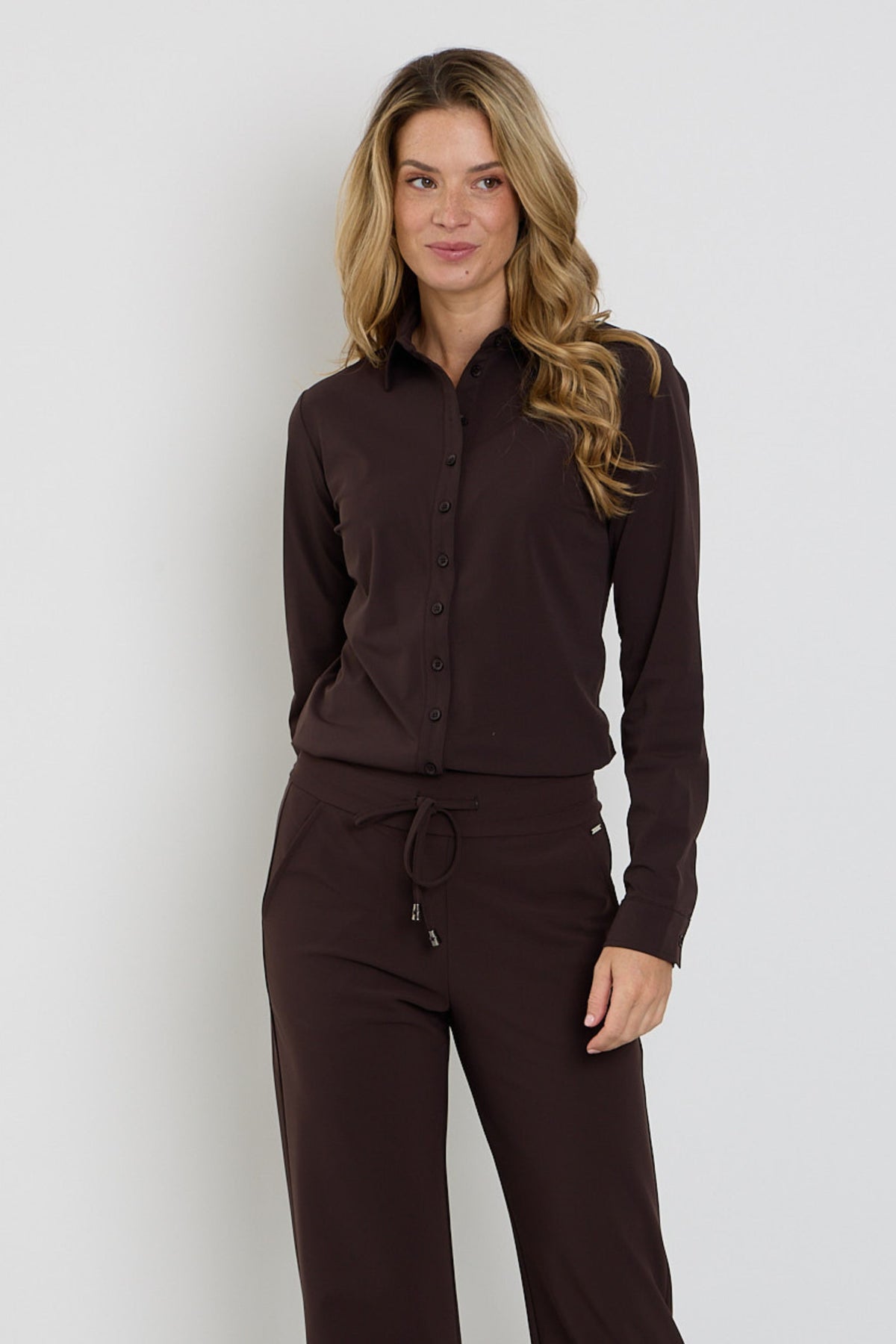 Donkere espresso travel blouse van Mi Piace, zittend met geknoopte kraag en lange mouwen, geschikt voor reizen en casual dragen.