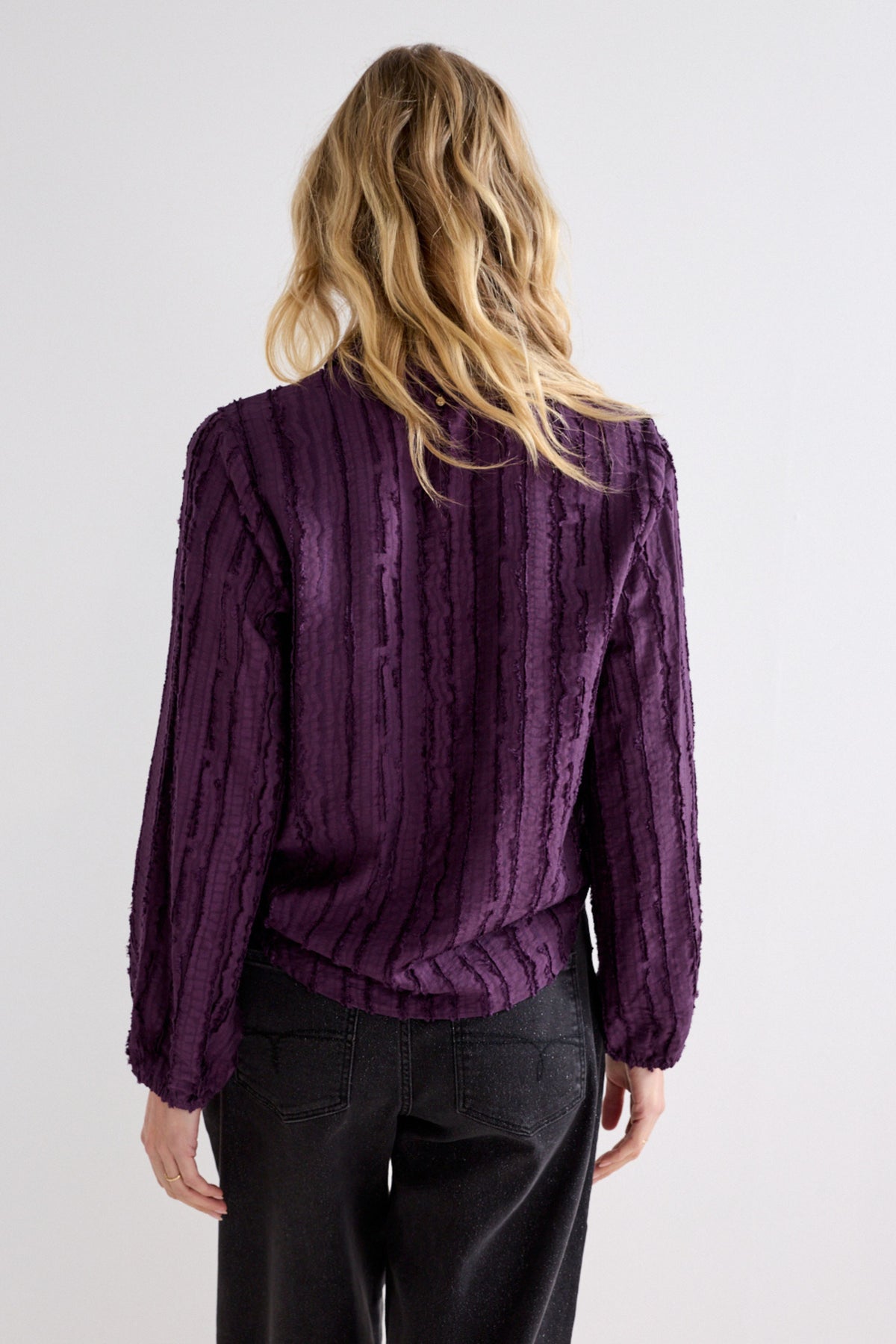 Donkere aubergine en zwarte gestreepte blouse van Tramontana met textuur en losse pasvorm op een modellens afbeelding.