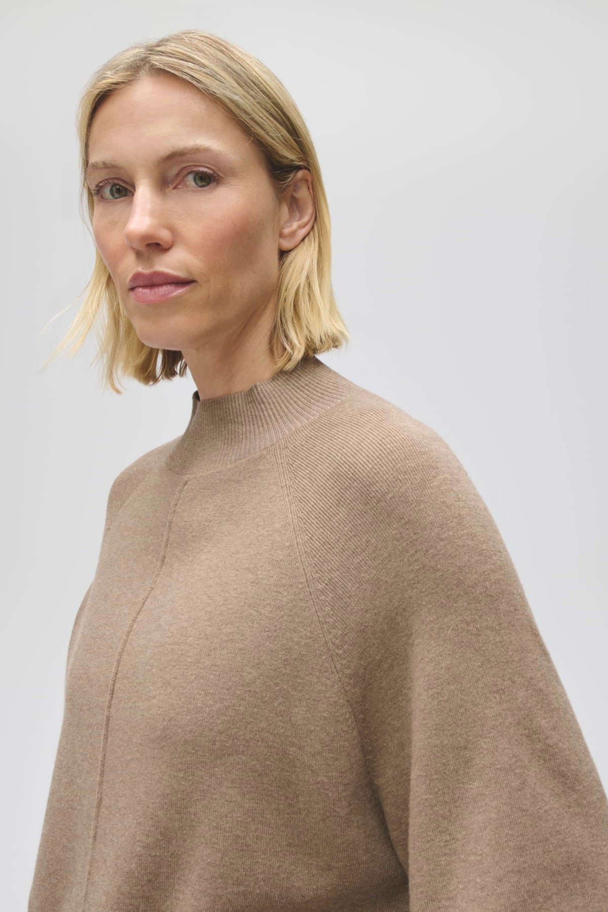 Lichte mocca trui van Opus met zachte stof en comfortabele pasvorm, gedragen door een model op een neutrale achtergrond.