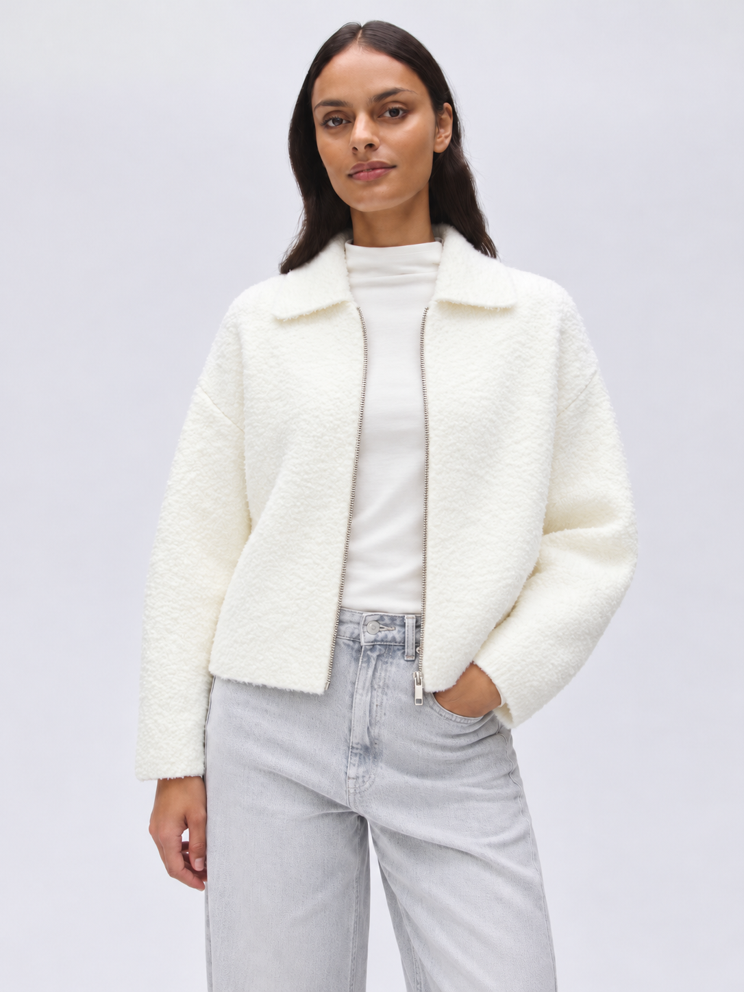 Opus Domira Soft Cream vest in een minimalistisch studioportret, gedragen door een model, zachte crèmekleur, modieus en eenvoudig.
