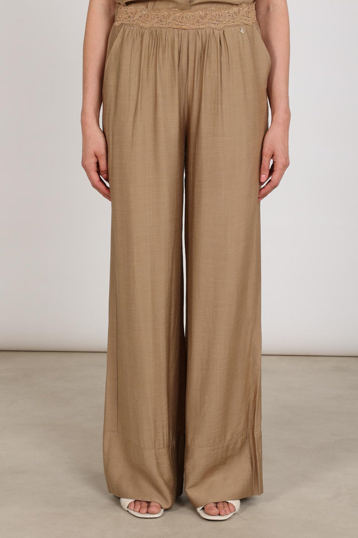 Camelkleurige Nukus Merel broek met rechte pasvorm en elastische taille, zichtbaar met ritssluiting en zakken.