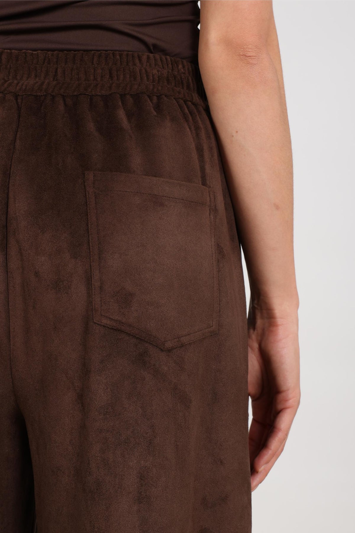 Nukus Bertie Suede broek in chocolade bruin, stijlvolle damesbroek met suède textuur, op een effen achtergrond.