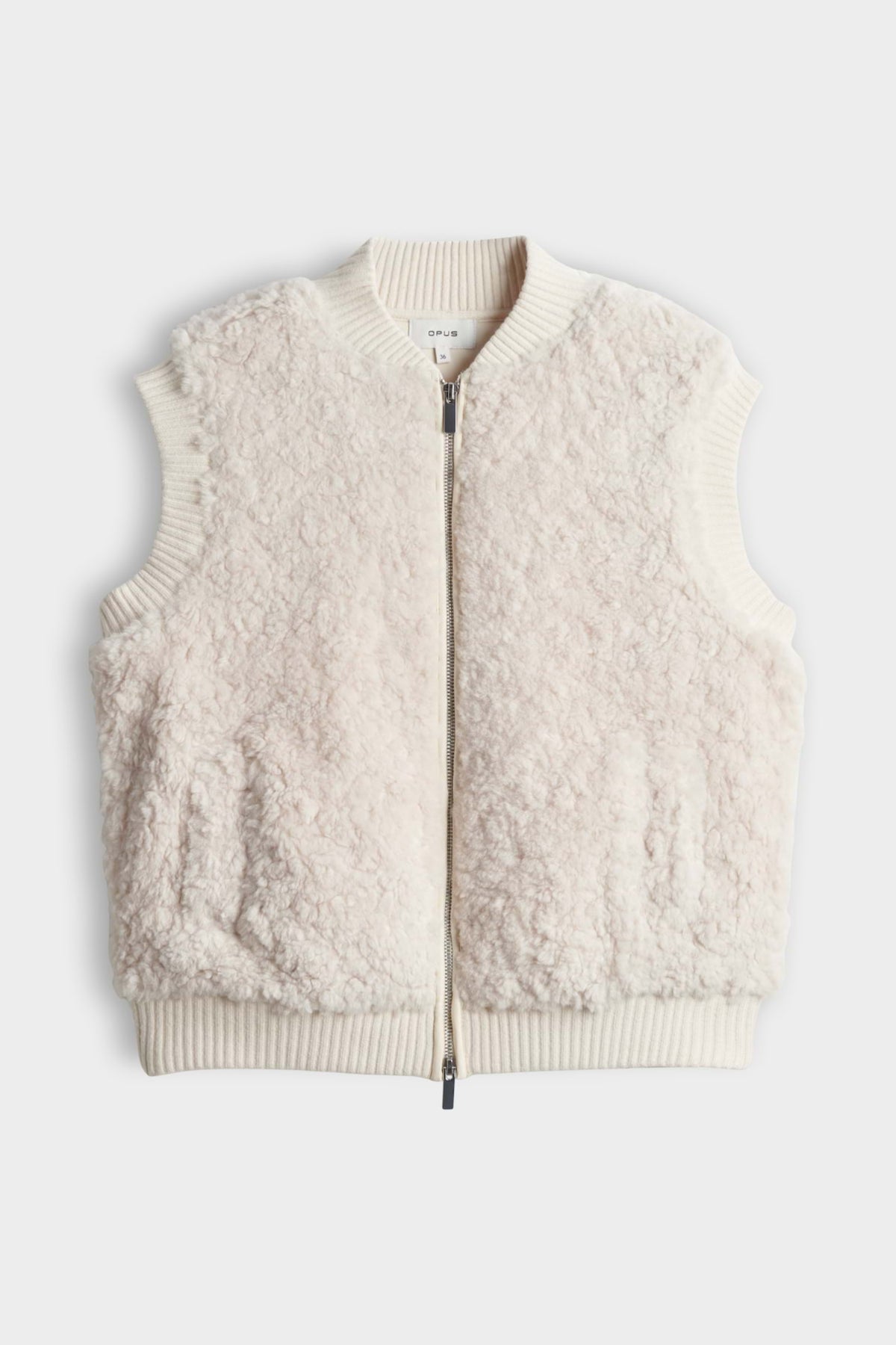 Licht crèmekleurig Opus Gilet Gaste Soft gedragen door een persoon, close-up van het zachte textuur en stijlvolle pasvorm.