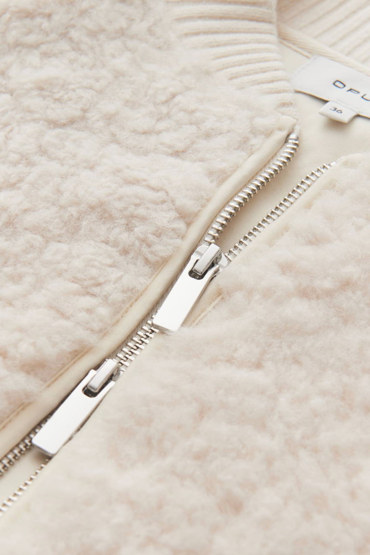 Licht crèmekleurige Opus Gilet Gaste Soft gedragen door een model, close-up van de zachte stof en pasvorm.