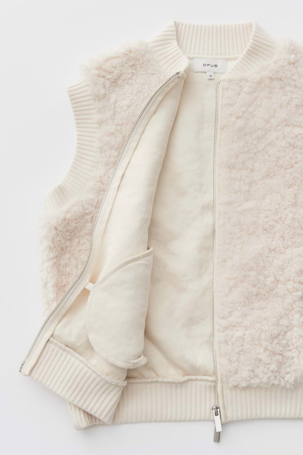 Licht crèmekleurig Opus Gilet Gaste Soft gedragen door een persoon, close-up van de zachte stof en stijlvolle pasvorm.