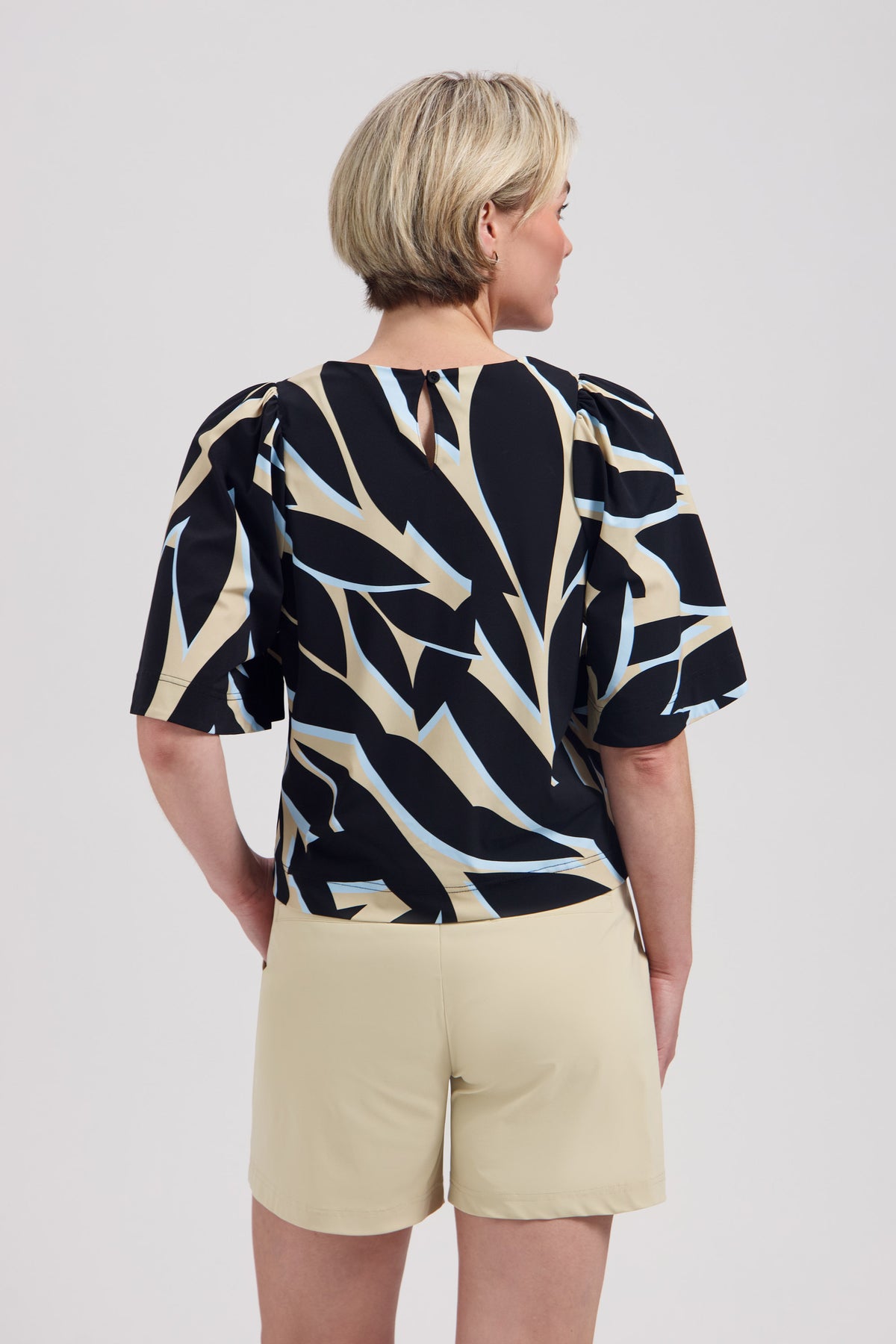 Lady Day travel top met Jason Leya print, korte snit en kleurrijk patroon, zichtbaar in de afbeelding.