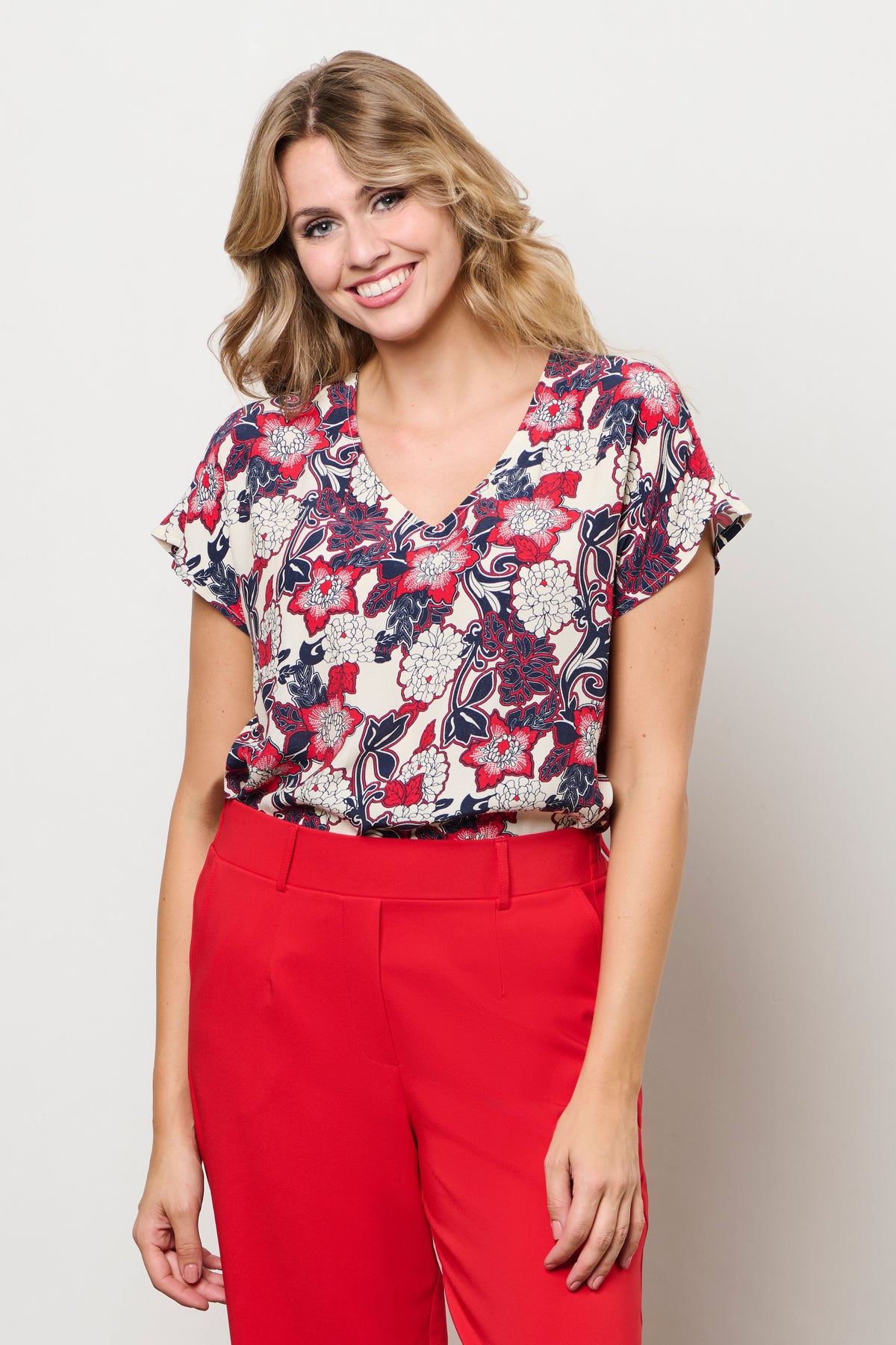 Kleurrijke top Amke Flower Red Multi van &Co woman, met bloemenprint en ronde hals, gedragen door een model.