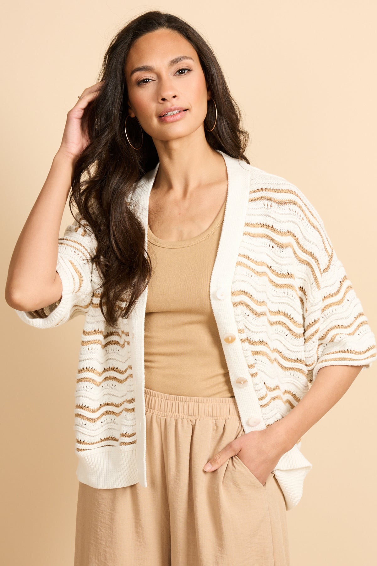 Witte wollen vest Helmi van G-maxx met breiwerk en camelkleurige details, gedragen door een model, close-up van de textuur.