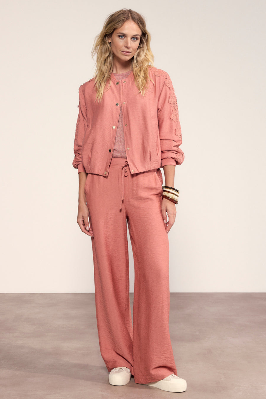 Lichte dusty roze brede pijpenbroek van Tramontana met riem, elegante en comfortabele damesmode op een witte achtergrond.
