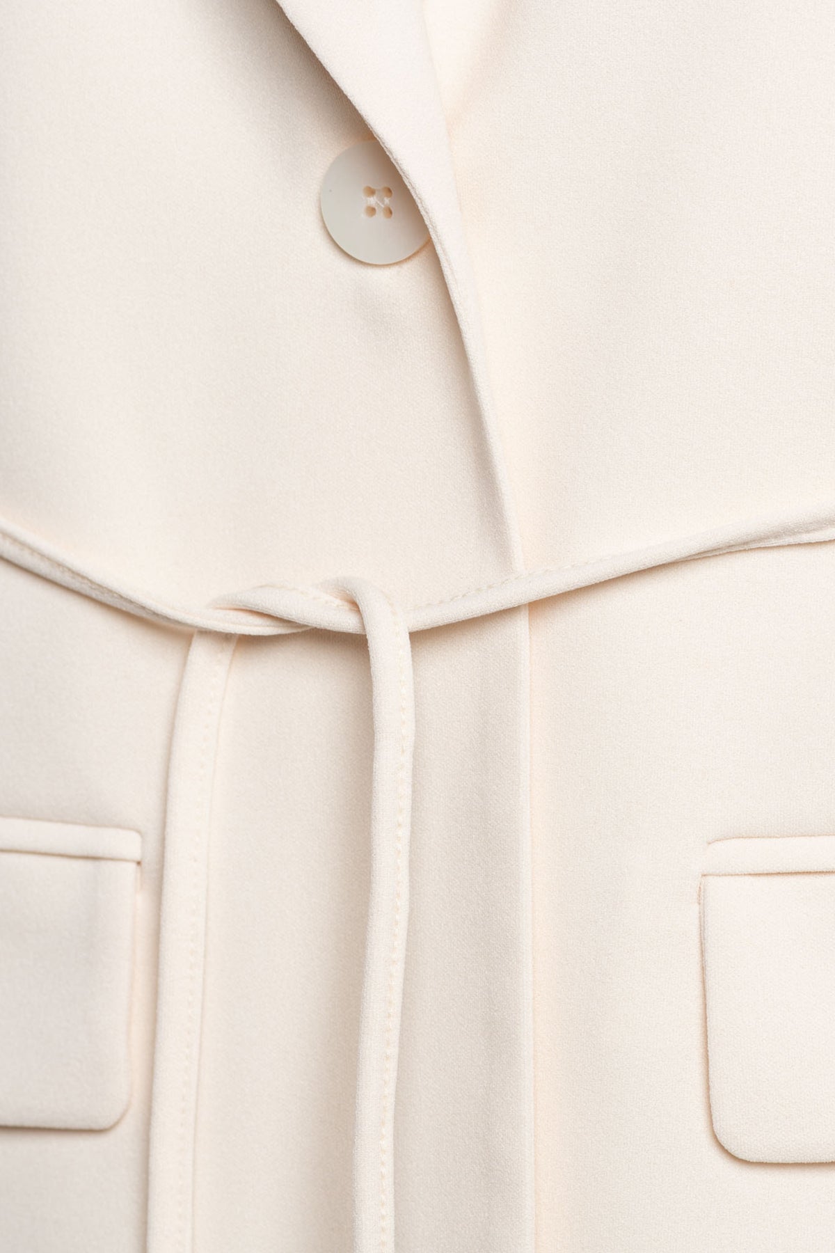 Blazer Gina Vanilla van &Co woman, lichtbeige blazer met knopen en reverskraag, gedragen door een model.