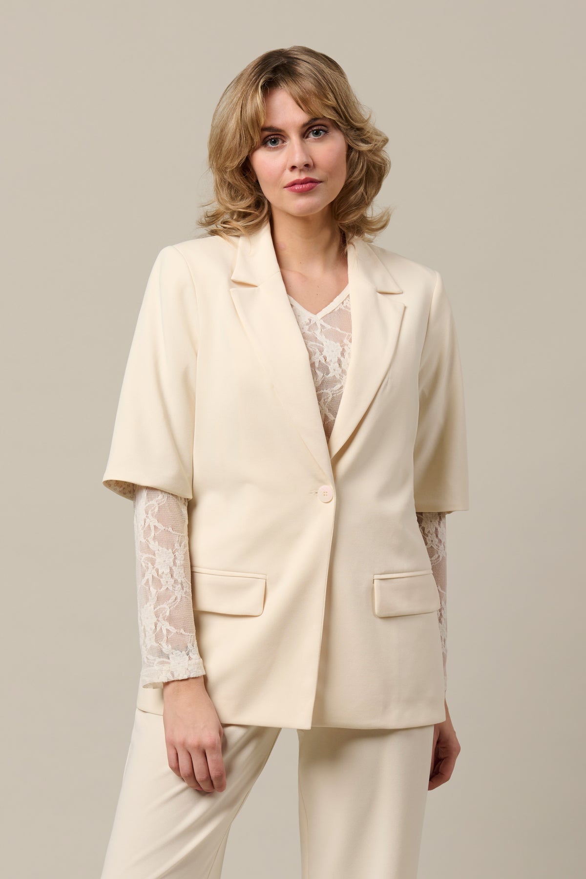Blazer Gina Vanilla van &Co woman, lichtbeige damesblazer met knoopsluiting en reverskraag, gedragen door een model.