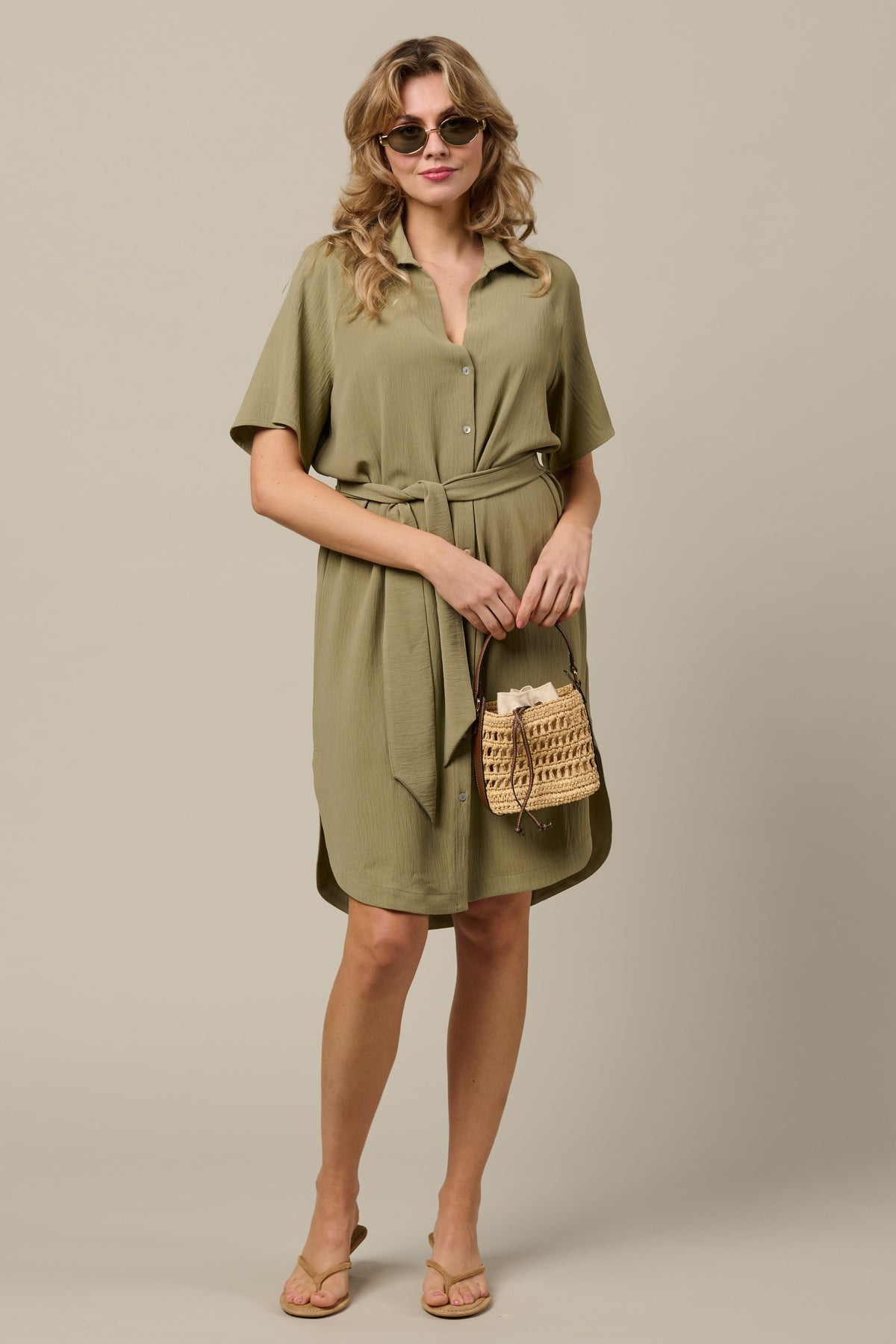 Lichte khaki jurk Margo van &Co woman, getoond met een vloeiende pasvorm en lange mouwen, geschikt voor casual en elegante gelegenheden.