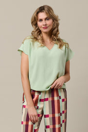 Macy Mint top van &Co woman, lichtgroene katoenen top met korte mouwen en ronde hals, gedragen door een model.