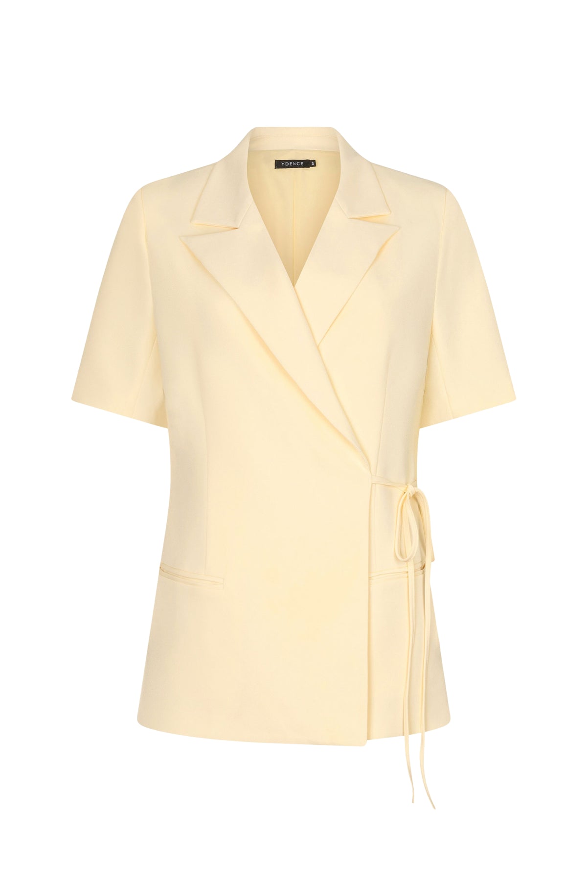 Lichte gele blazer van Ydence met stijlvolle pasvorm, gedragen door een model, close-up van de stof en details.