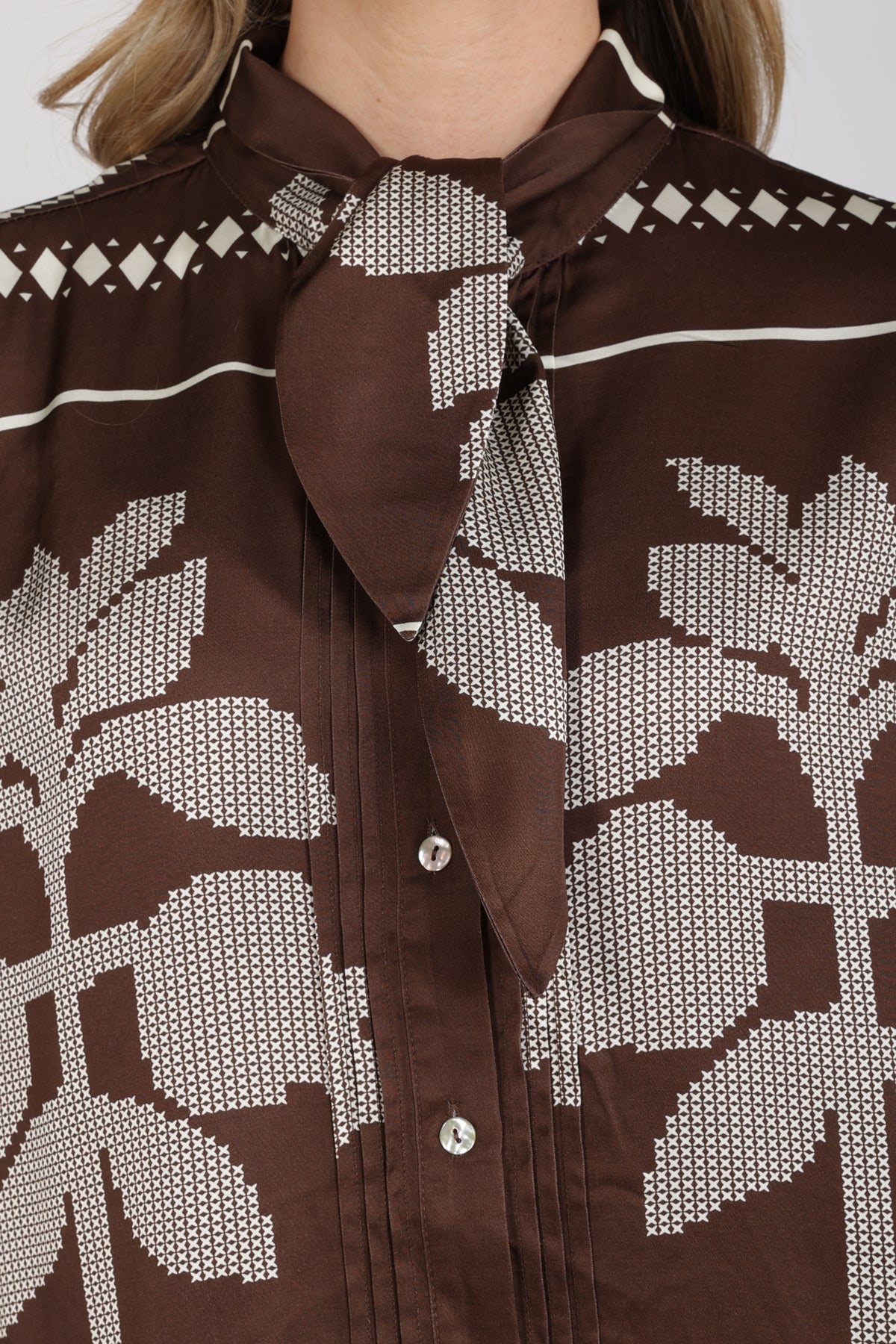 Nukus blouse Alexandra Tie Cross in chocolade en offwhite, met gekruiste details en stijlvolle pasvorm, op model gedragen.