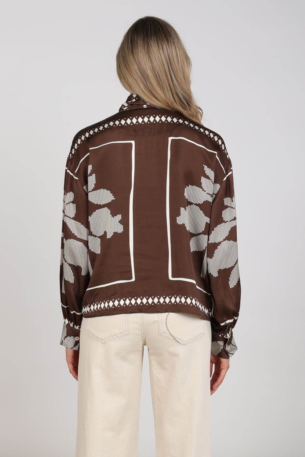 Nukus blouse Alexandra Tie Cross in chocolade en offwhite, met gekruiste details en losvallende pasvorm, gelegen op een witte achtergrond.