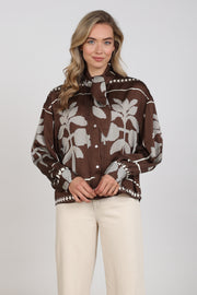 Nukus blouse Alexandra Tie Cross in chocolade en offwhite, met stijlvolle details en elegante snit, gedragen door een model.