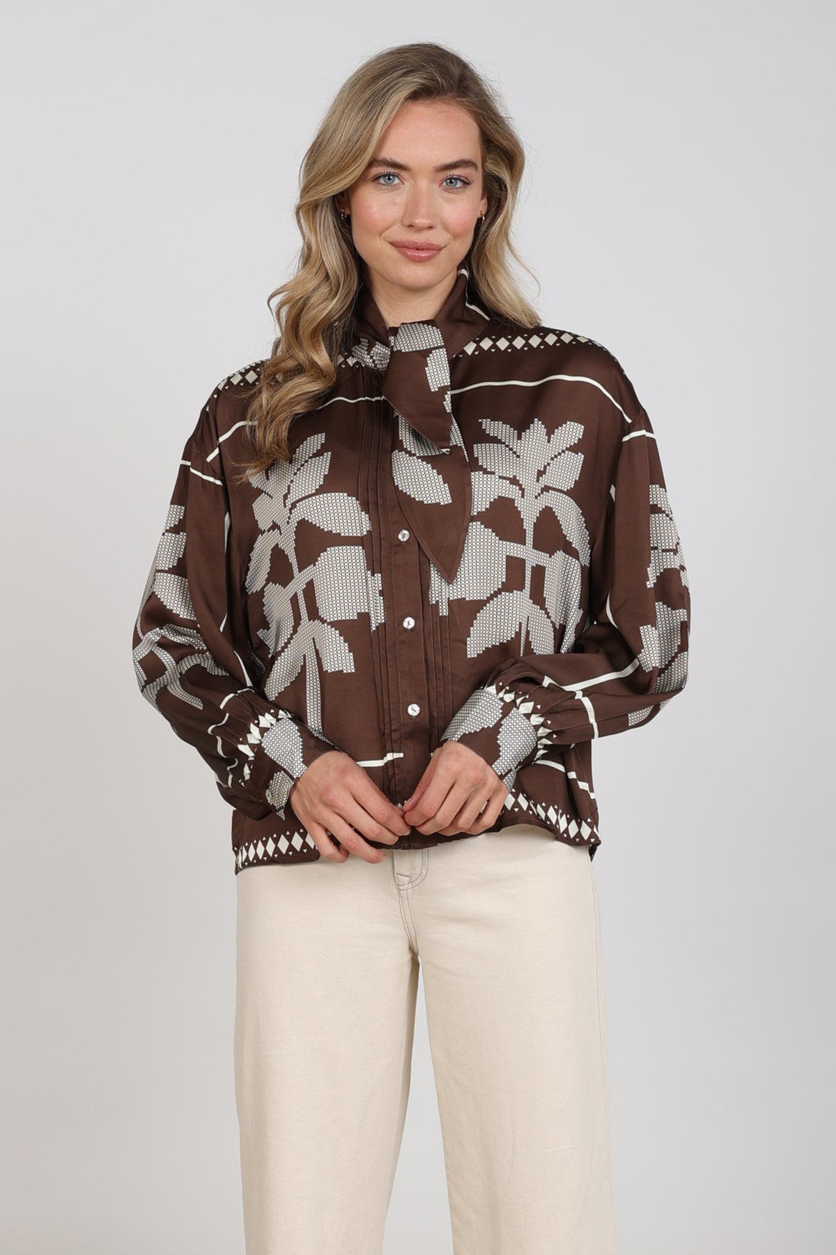 Nukus blouse Alexandra Tie Cross in chocolade en offwhite, met stijlvolle details en elegante snit, gedragen door een model.