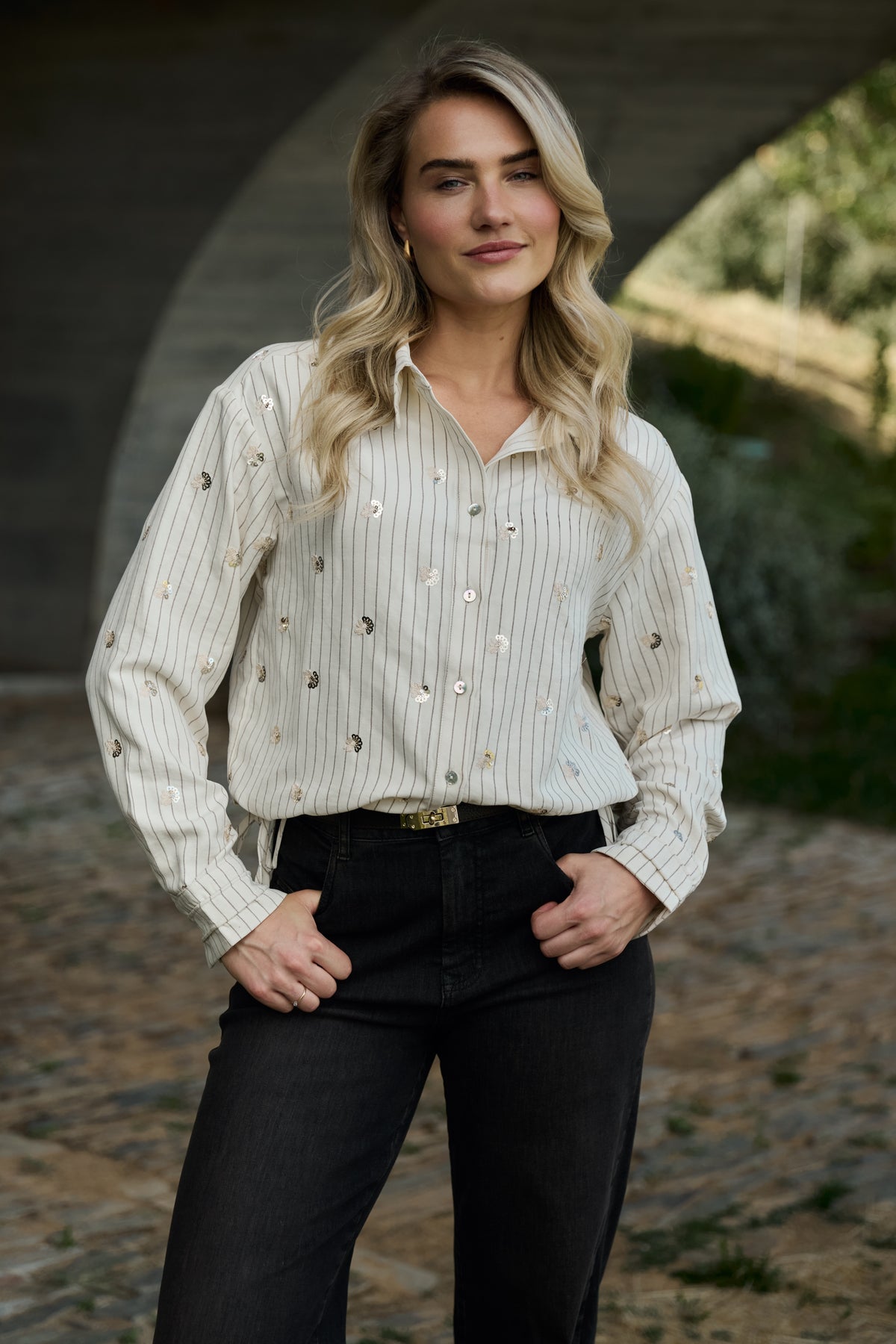 Offwhite blouse Aaliya Paillet van Nukus met glanzende details en elegante pasvorm, zichtbaar op de afbeelding.