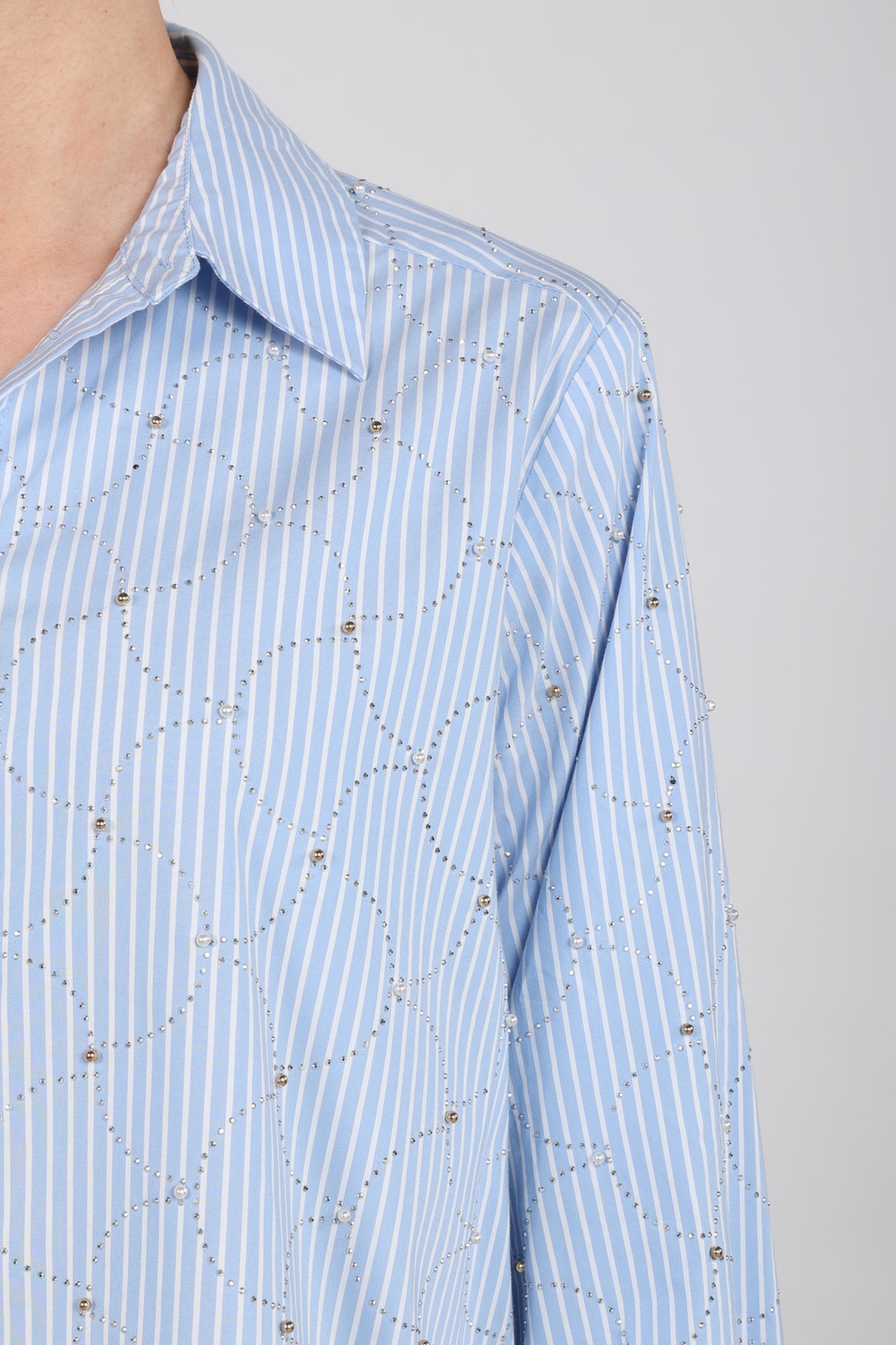 Offwhite Nukus blouse Nowi met blauwe strepen en stenen details, korte mouwen en losse pasvorm op een model gedragen.