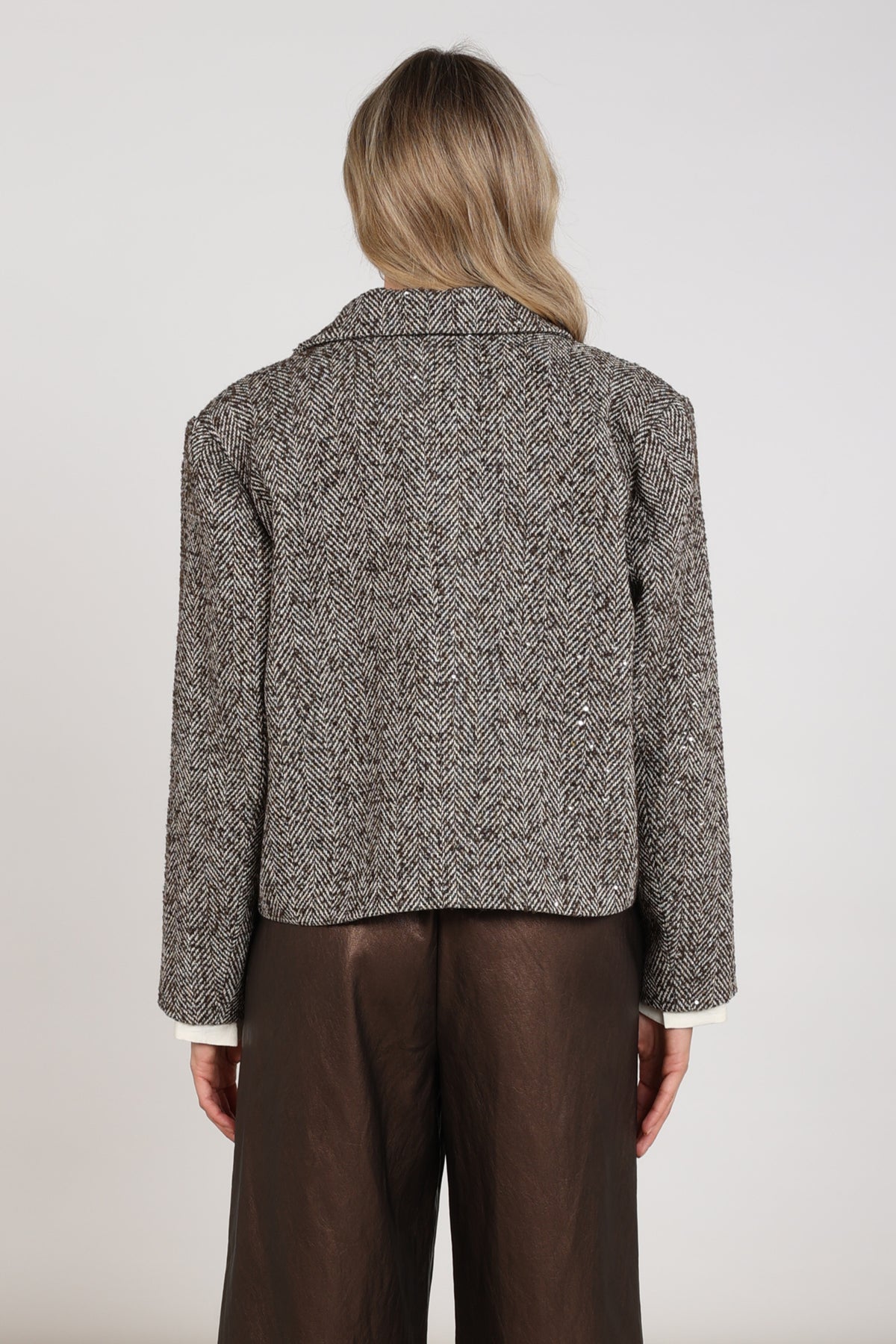 Donkere chocolade Daphne Herringbone jas van Nukus, getextureerd met een geblokt patroon, op een model gedragen
