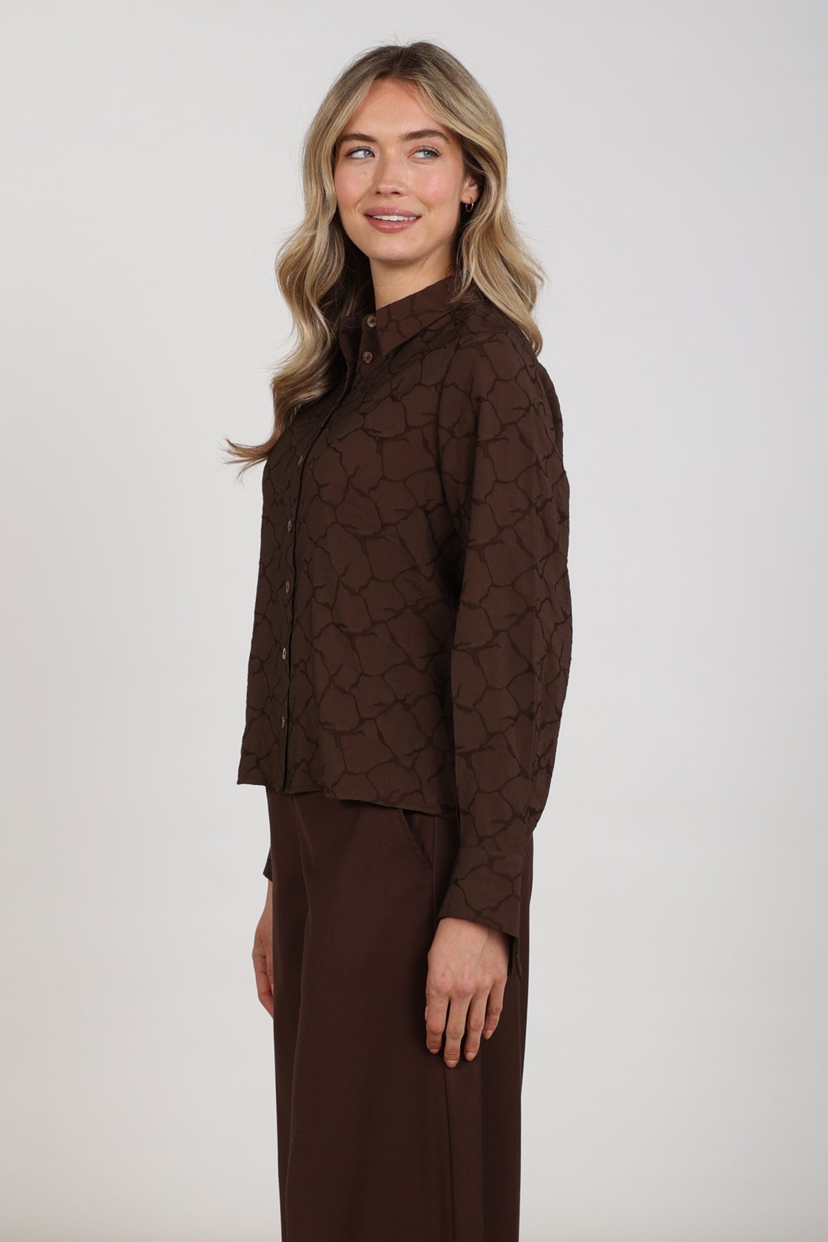 Donkere chocolade blouse Alice van Nukus met wijde mouwen en knoopsluiting, gedragen door een model.