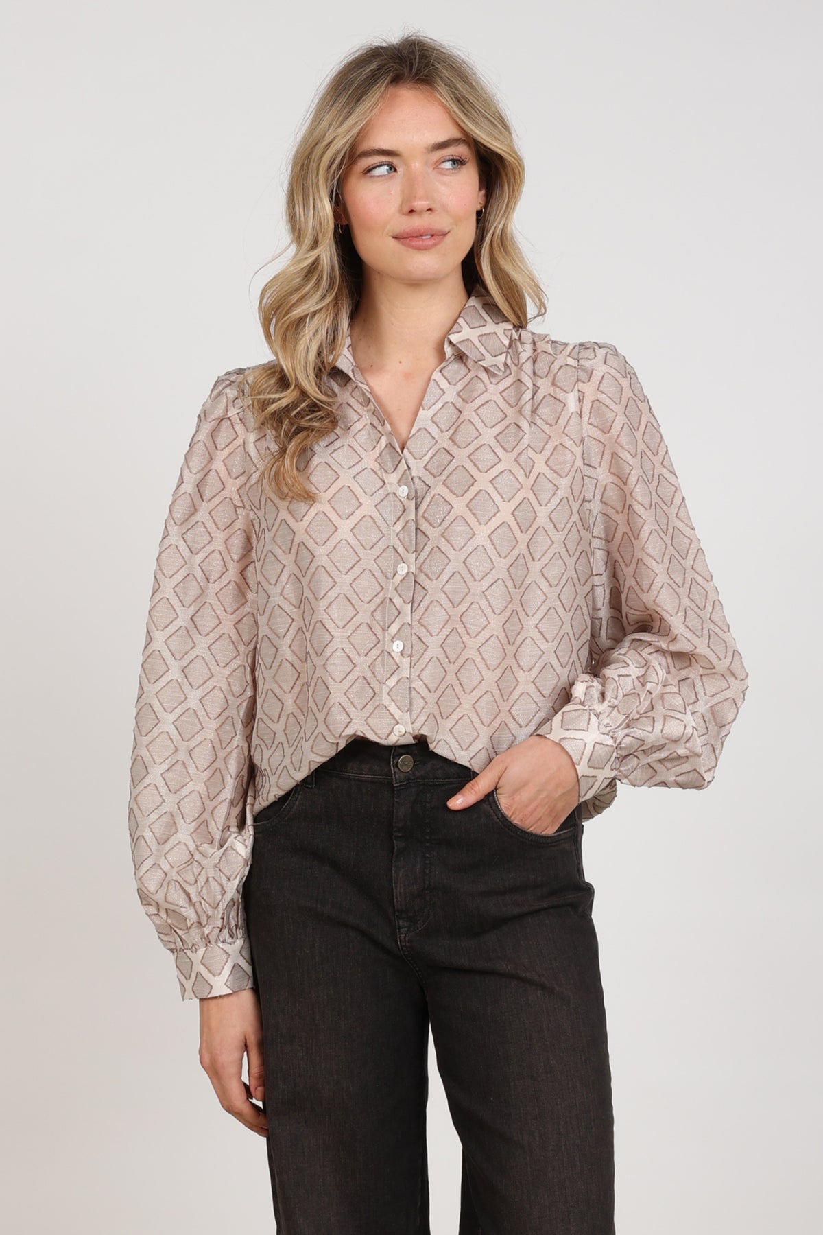 Nukus Antonella patroon blouse in zandkleur met bloemenprint, korte mouwen en knoopsluiting, gedragen door een model.