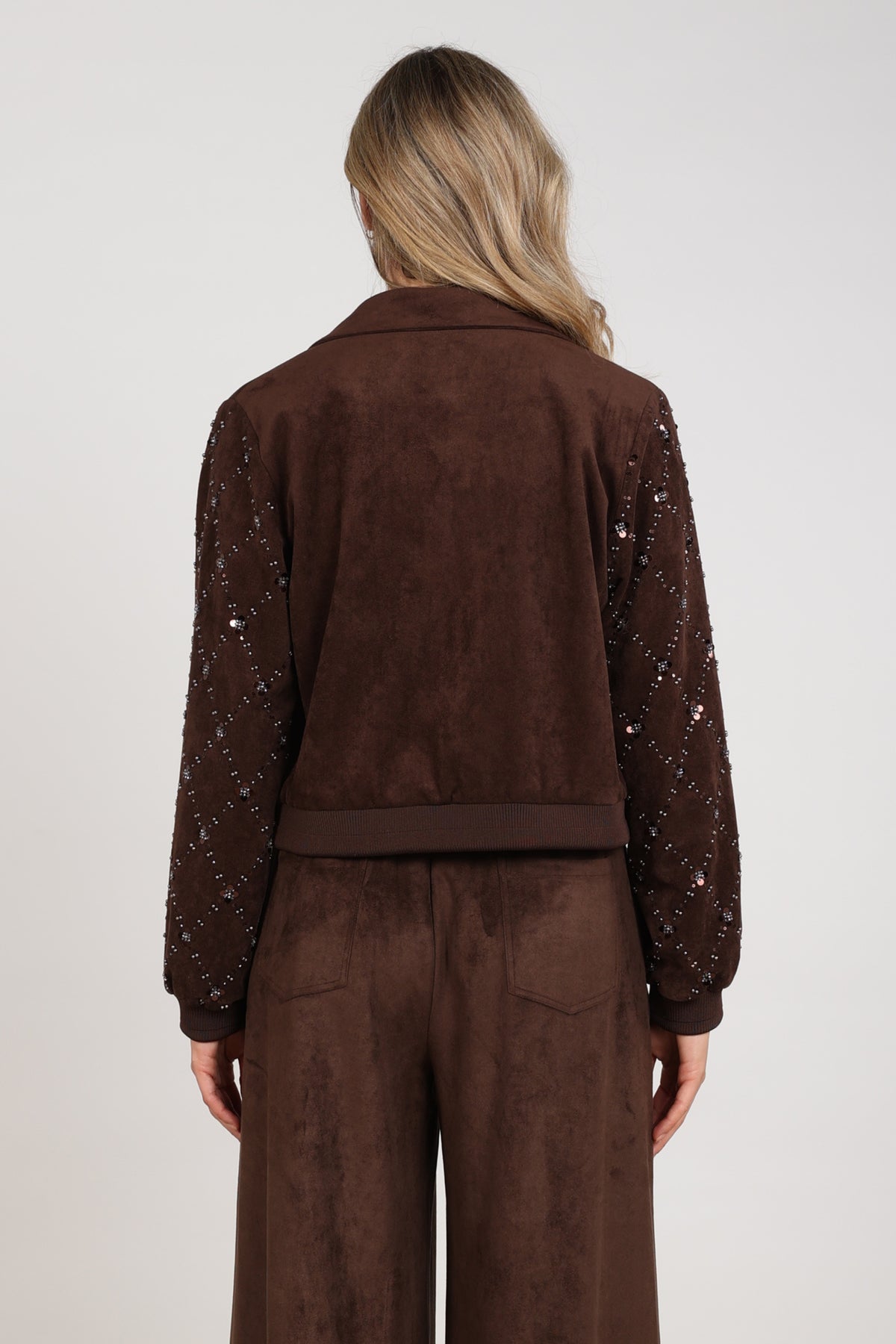 Donkere suède Daisy jas van Nukus met afneembare capuchon en knoopsluiting, getoond in een close-up op een model.