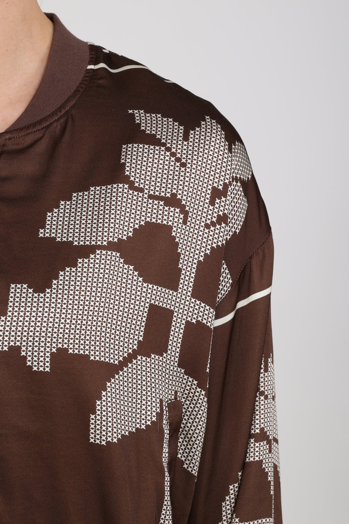 Donkere chocolade en offwhite Nukus Davina Cross jas met gespdetails en ritssluiting, gedragen door een model.