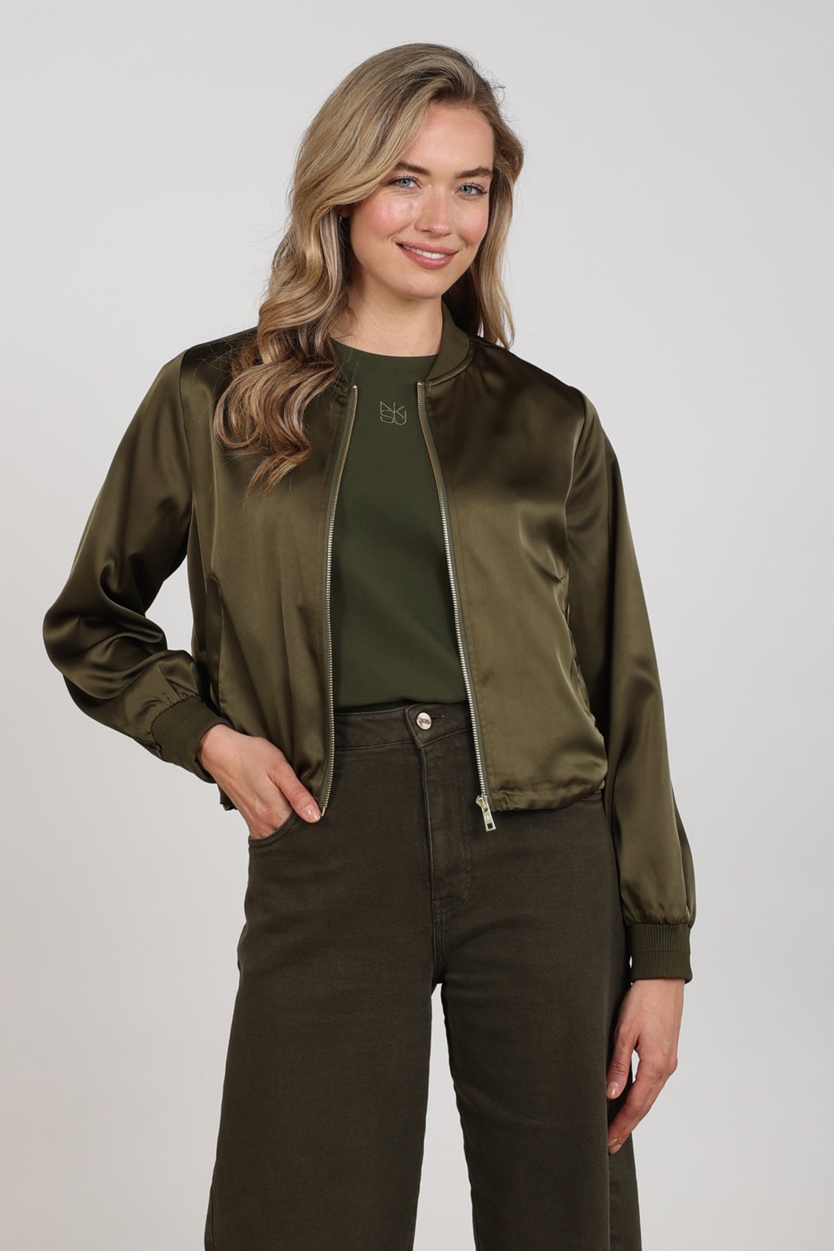 Nukus Dena Shiny Moss jas met glanzende afwerking en ritssluiting, gedragen door een model op de foto.