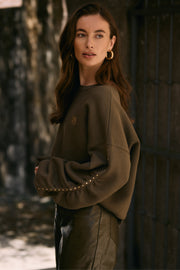 Donkere groene trui Olivia Studs van Nukus, zachte stof en comfortabele pasvorm, gedragen door een model.