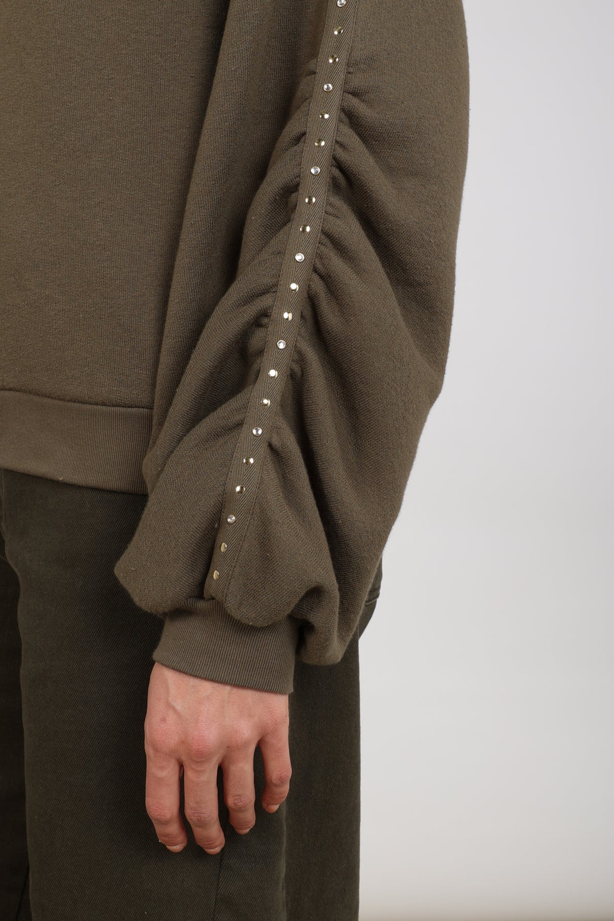 Donkere moss trui Olivia Studs van Nukus, zachte stof en ronde hals, gedragen door een model.