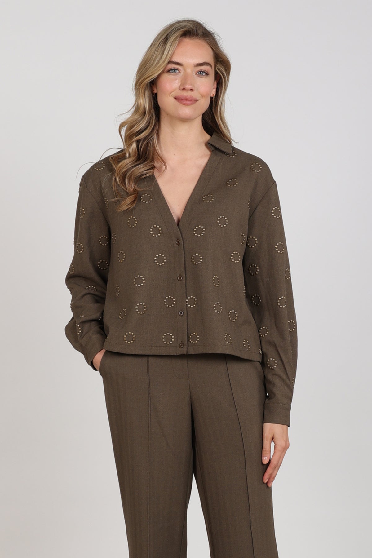 Blouse Anika Studs Moss van Nukus, lichtgroene blouse met stijlvolle details en knoopsluiting, gedragen door een model.