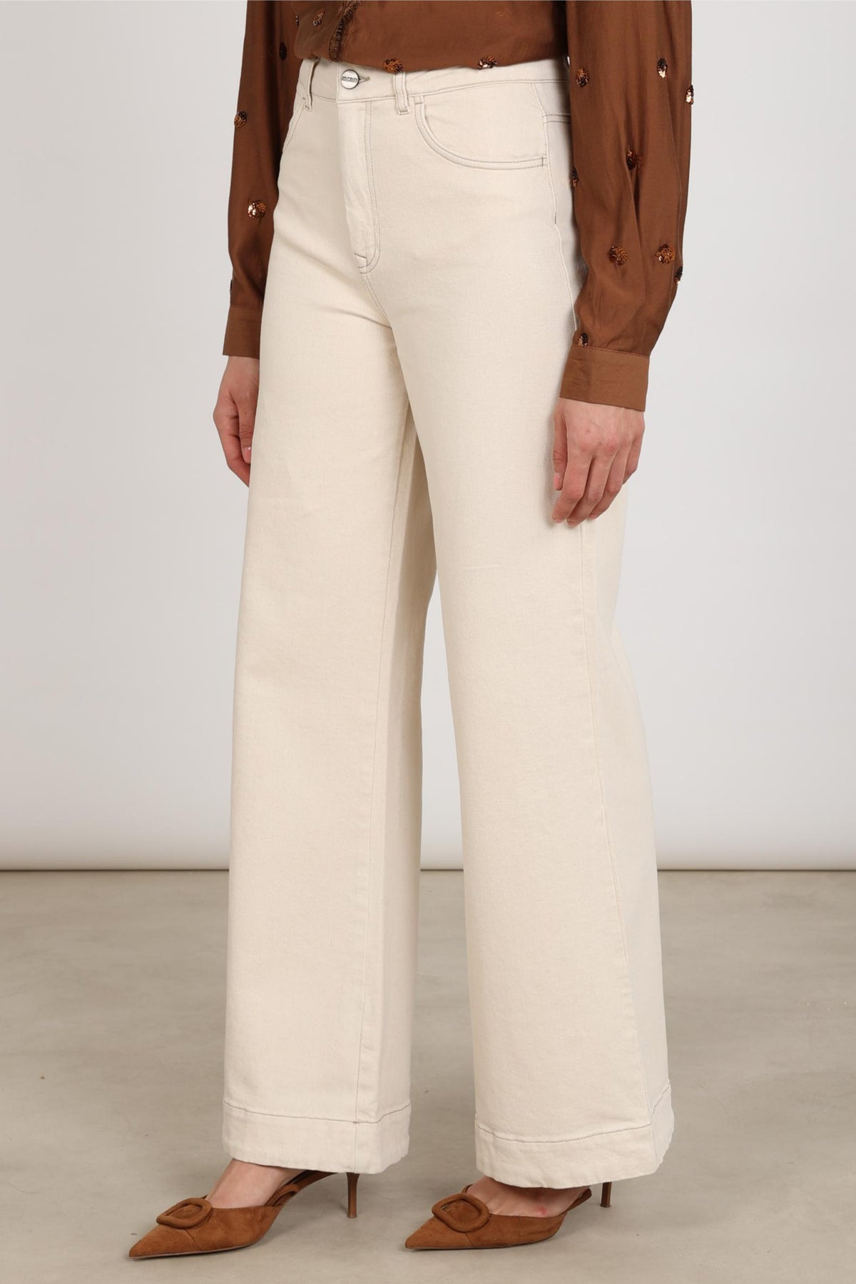 Donkere jeans van Nukus Abby Offwhite met rechte snit, zichtbaar met rits en zakken, gelegd op een witte achtergrond.