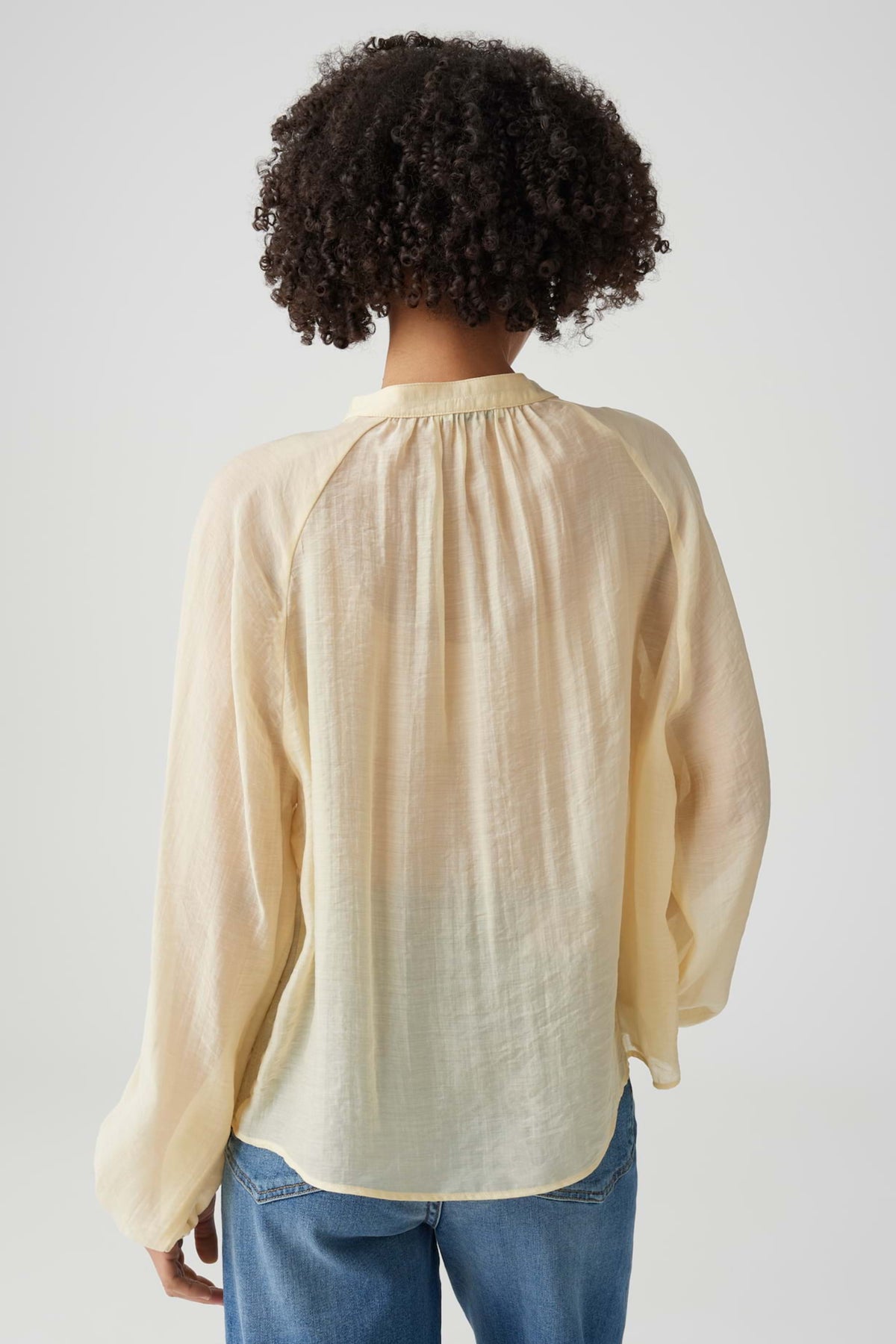 Witte blouse Fabrielle Honey Butter van Opus met ronde hals en losse pasvorm, hangend aan een kapstok.