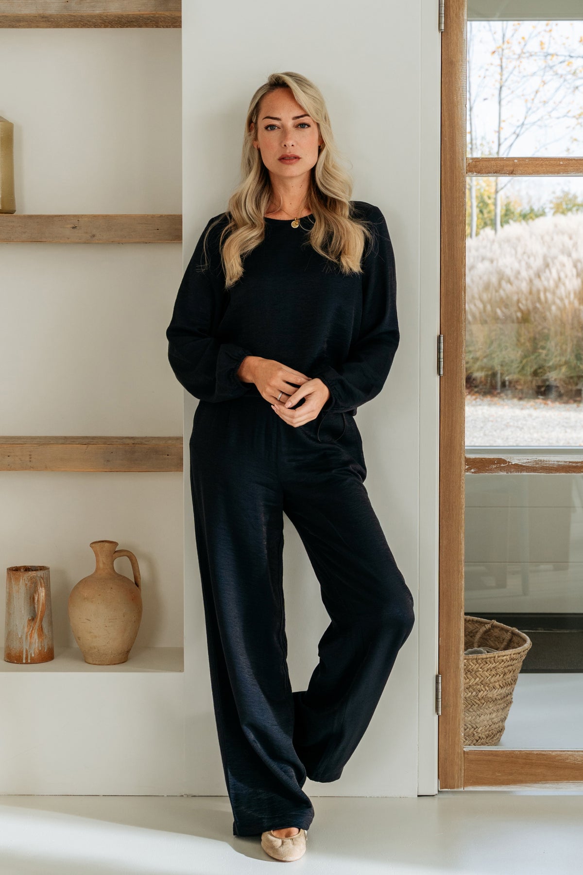 Navy blauwe broek Abelie van &Co woman, getoond in een overzichtsfoto met een model die de broek draagt.