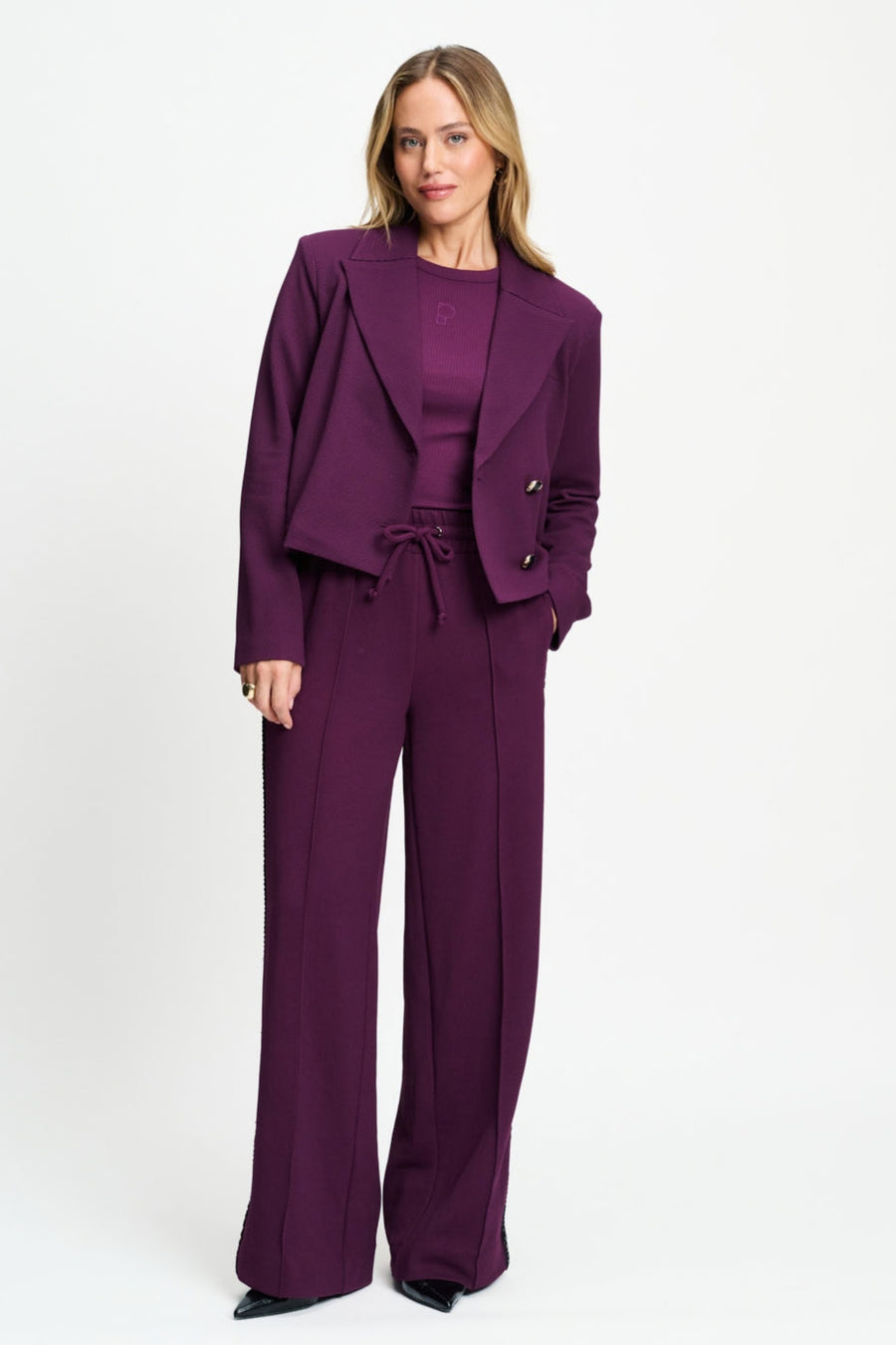 Donkere paarse broek Leah van POM Amsterdam, vlakke taille en comfortabele pasvorm, zichtbaar op de afbeelding.