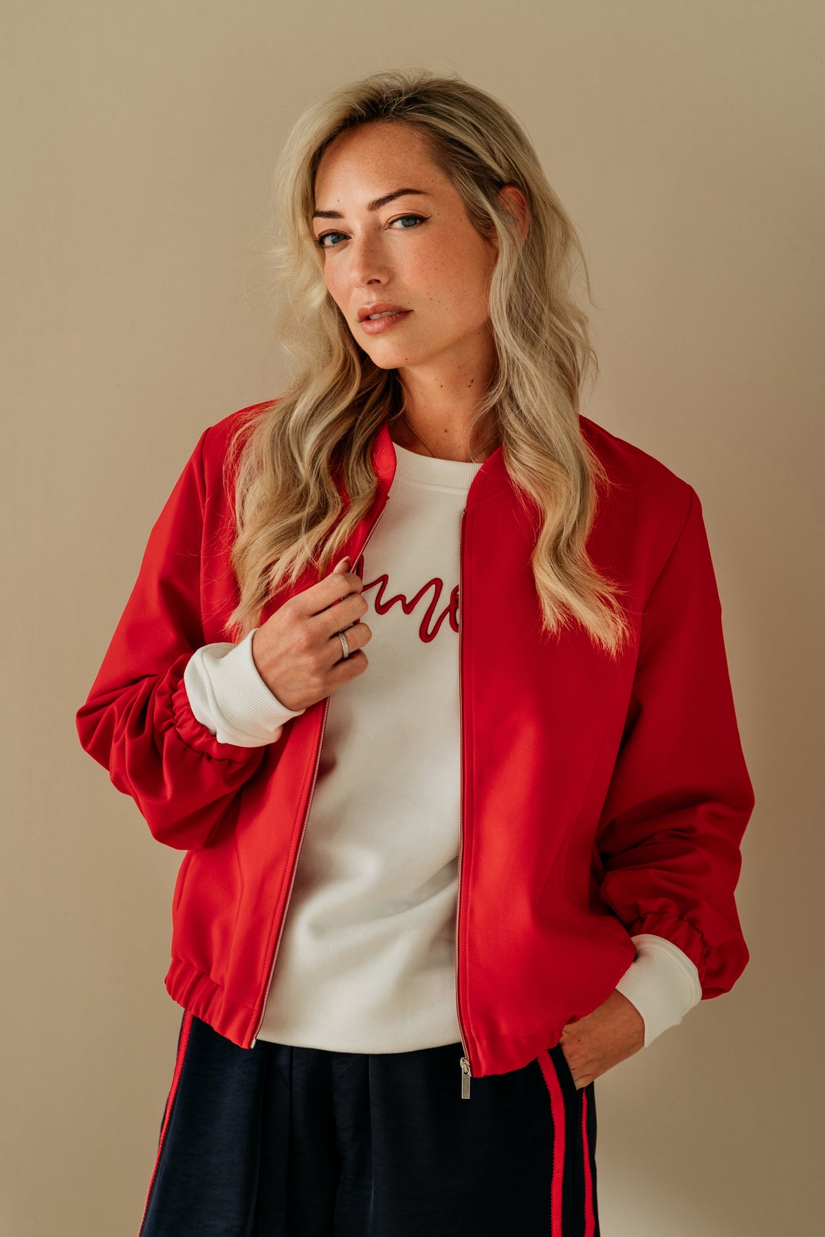 Zelda rode jas voor dames van &Co woman, getoond op een mannequin, met ritssluiting en kraag.