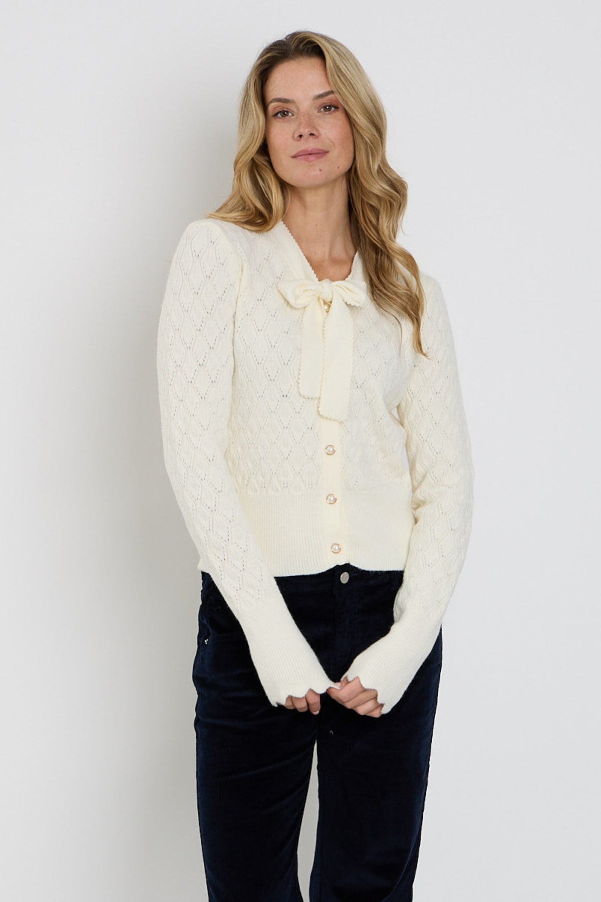 Offwhite Mi Piace vest met ajour en strikdetail, zachte textuur en stijlvolle uitstraling, ideaal voor casual en chique gelegenheden.
