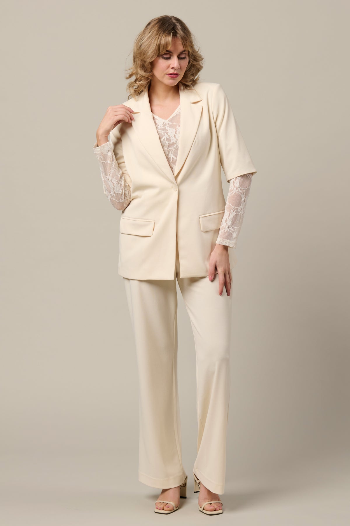 Lichtbeige Gina Vanilla blazer van &Co woman, getailleerd met knopen en reverskraag, gedragen door een model.