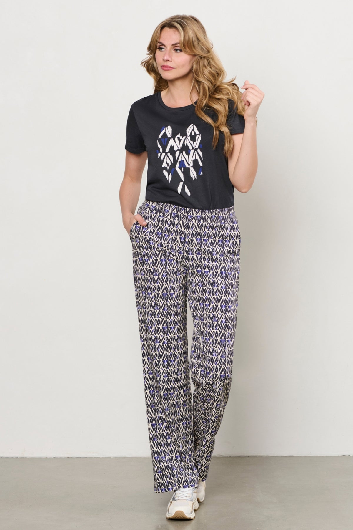 Navy blauwe travel broek Patrice Graphic van &Co woman met multicolor print, comfortabel en stylish voor reizen.
