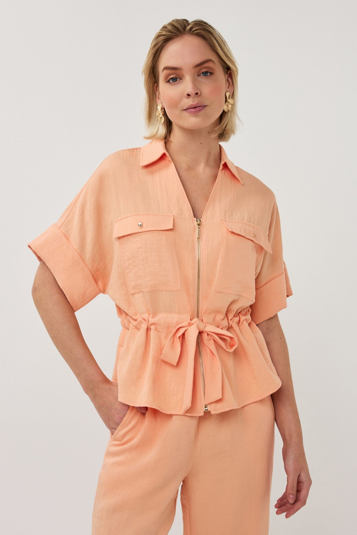 Zwarte blouse van EsQualo met rits en fijne crinkle-textuur, model Bellini SP26.10038, casual en elegant voor elke gelegenheid.